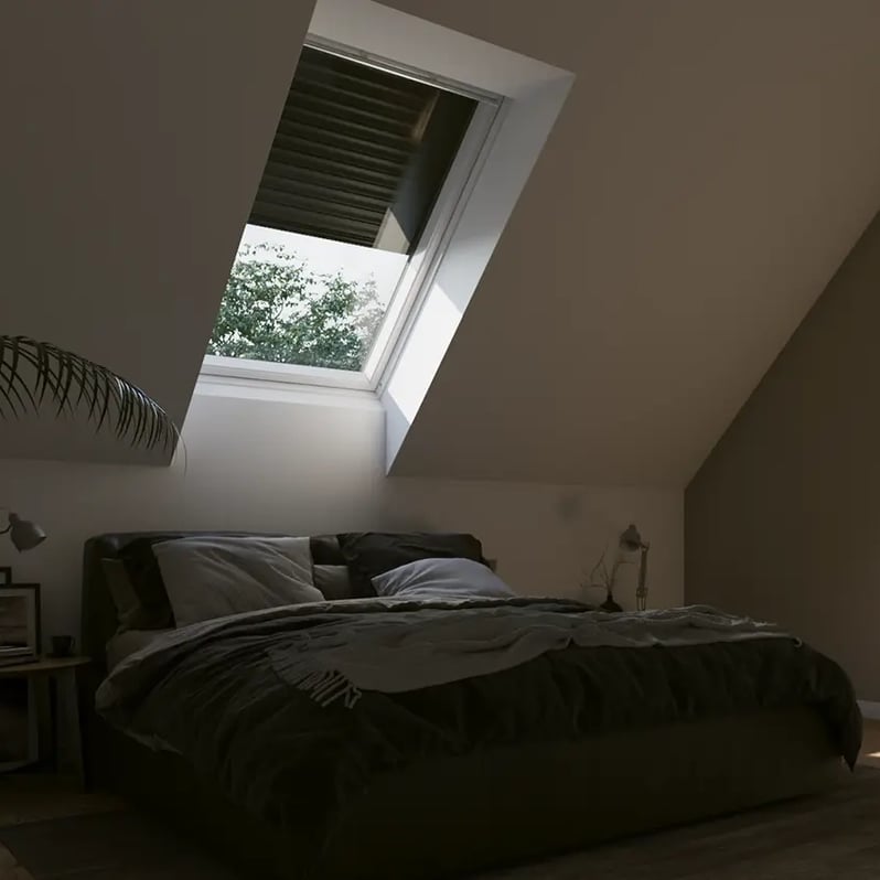 Attic bedroom with sloped ceiling and VELUX roof window, natural light entering.