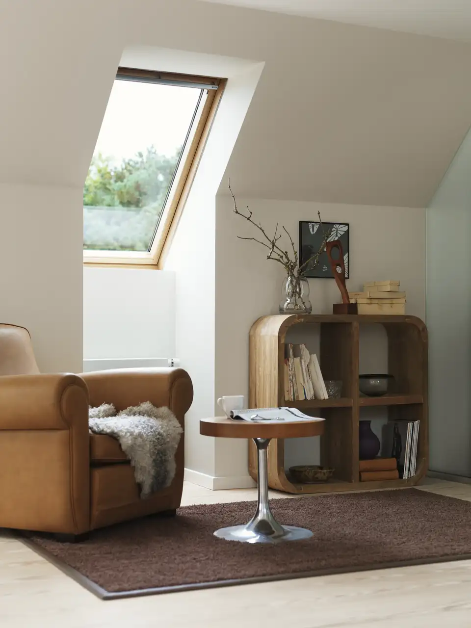 Soggiorno in mansarda con arredamento dalle linee curve in stile vintage, illuminato da una finestra per tetti.