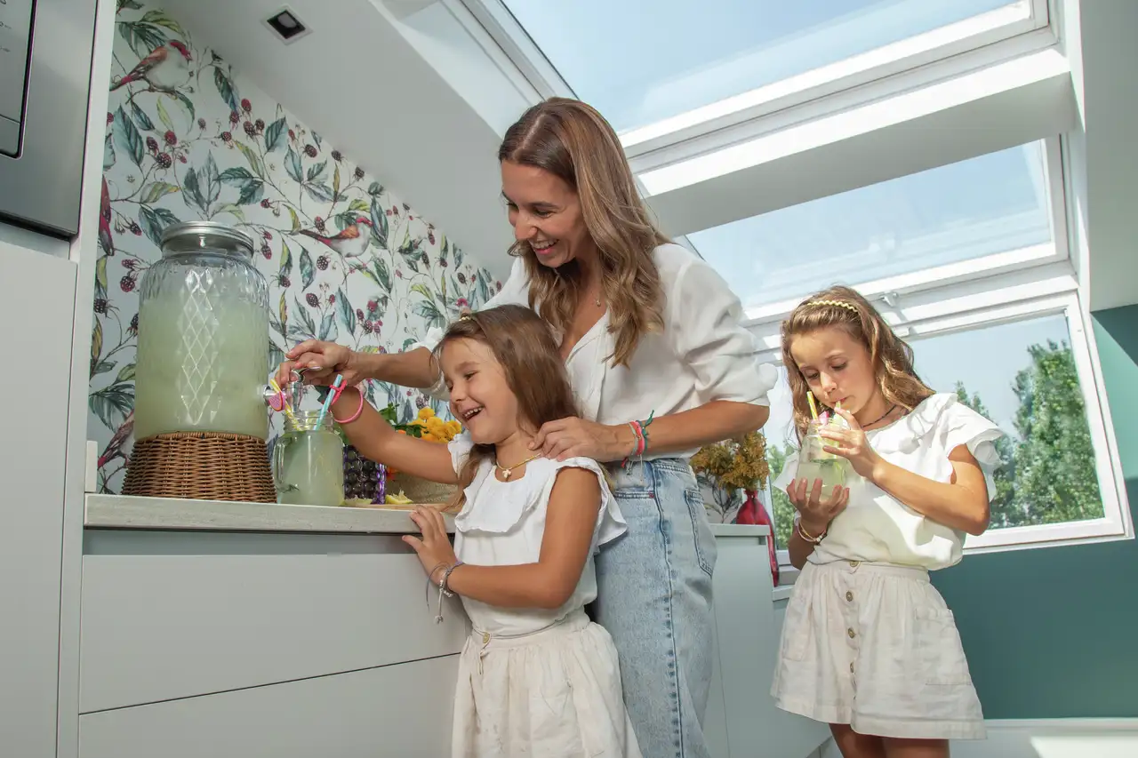 Mujer con niñas en cocina abuhardillada con ventanas de tejado 