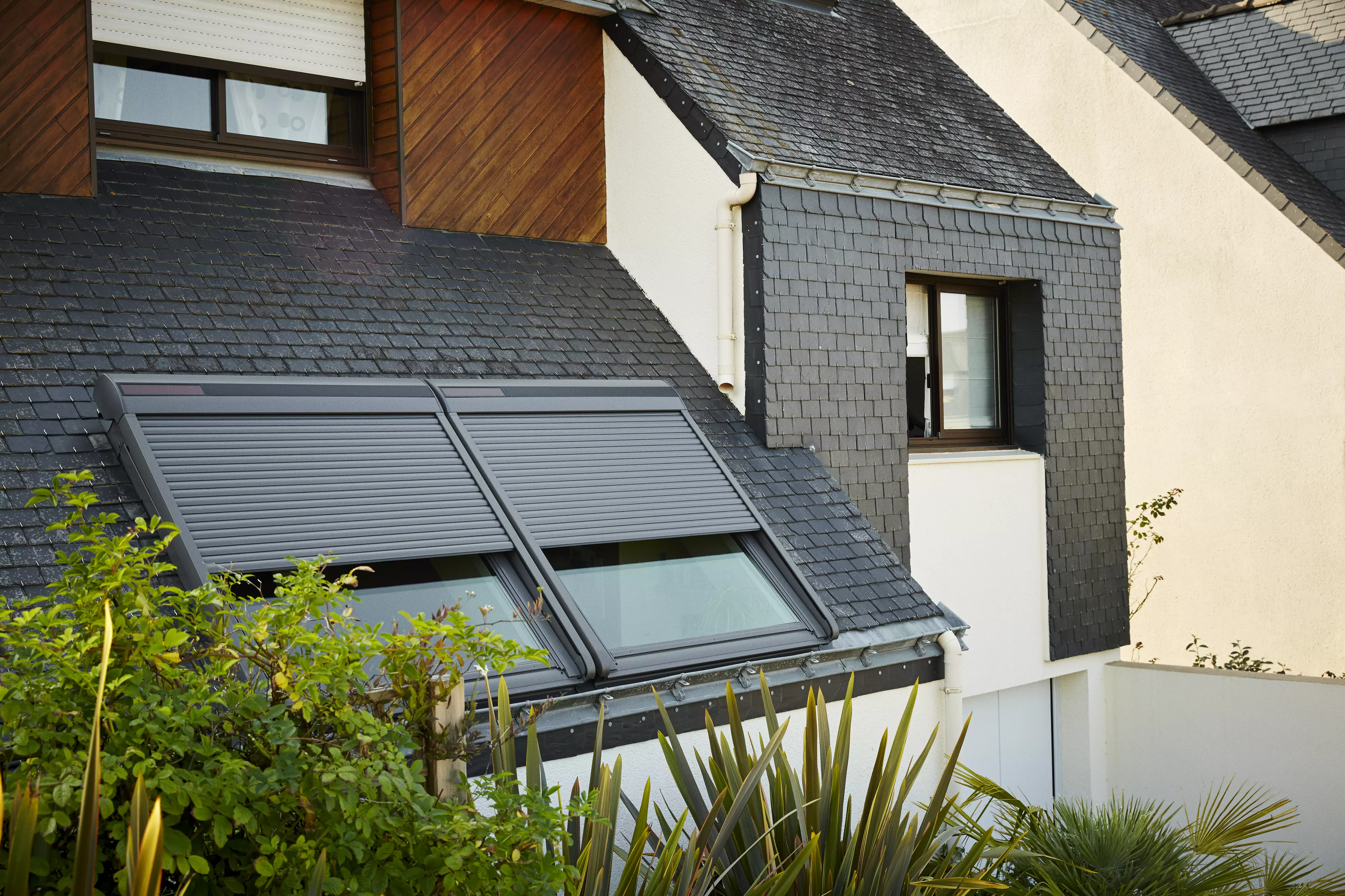Une maison moderne avec des panneaux solaires sur le toit, illustrant un choix d’énergie durable. La fenêtre de toit Velux ajoute une touche de lumière naturelle à l’intérieur de la maison.