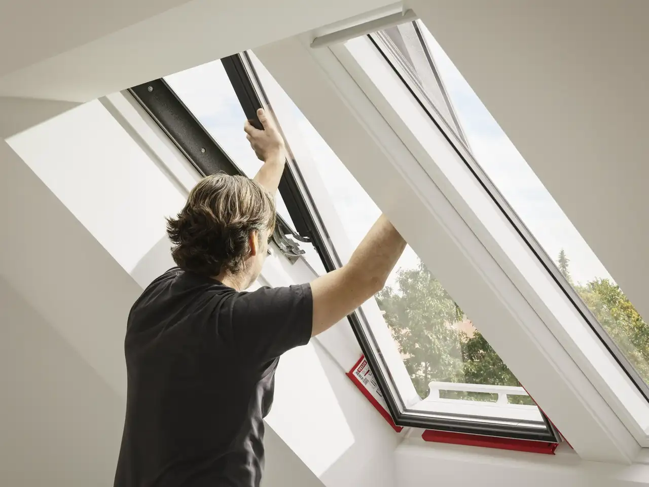 Un uomo installa una nuova finestra per tetti VELUX