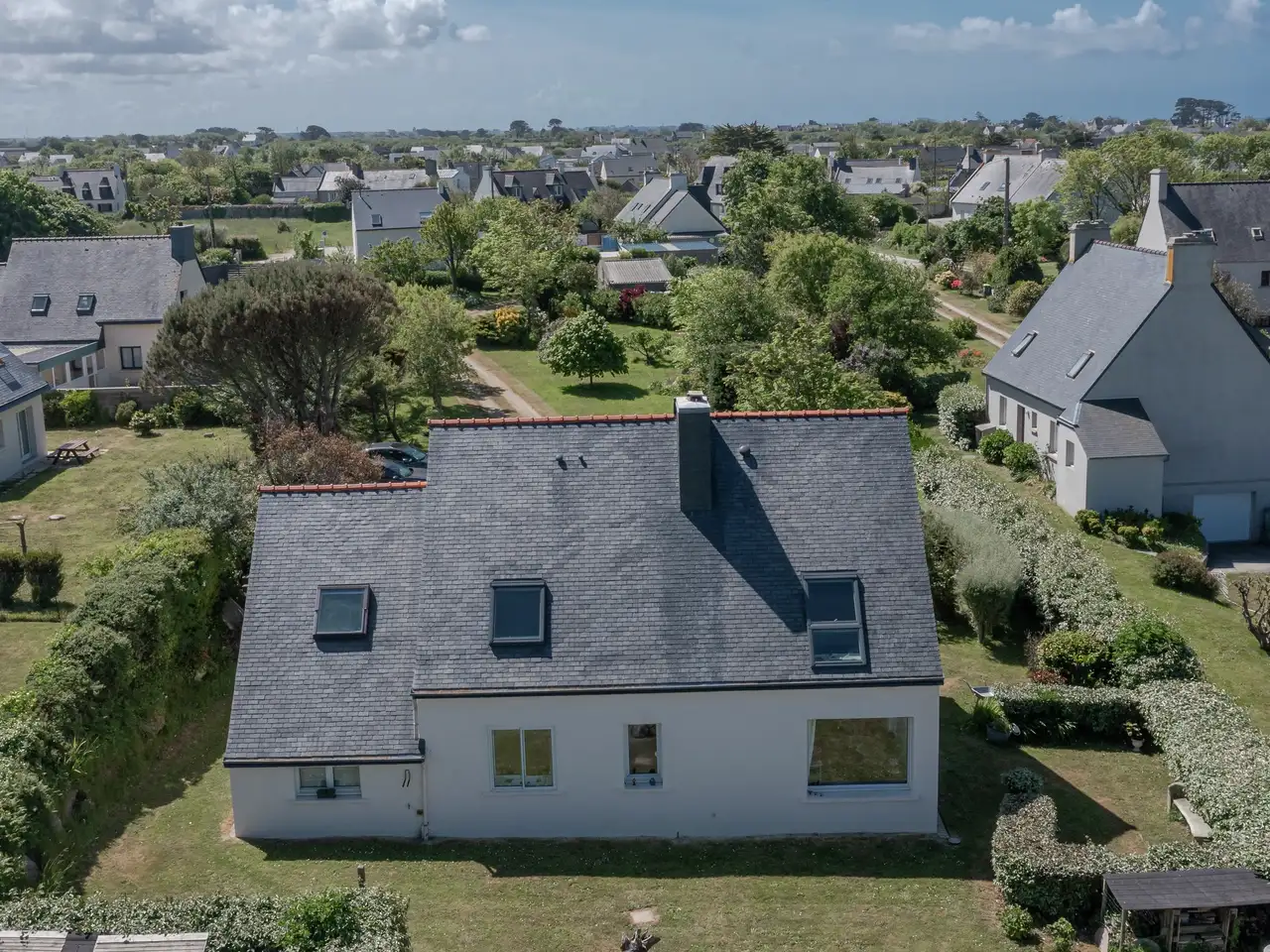 maison avec toit à deux pans et fenêtres de toit VELUX, entourée de verdure