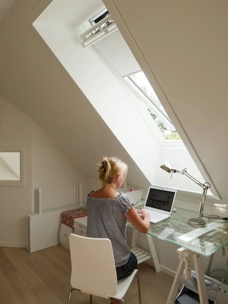  Une femme travaille à son bureau sous une grande fenêtre de toit VELUX 