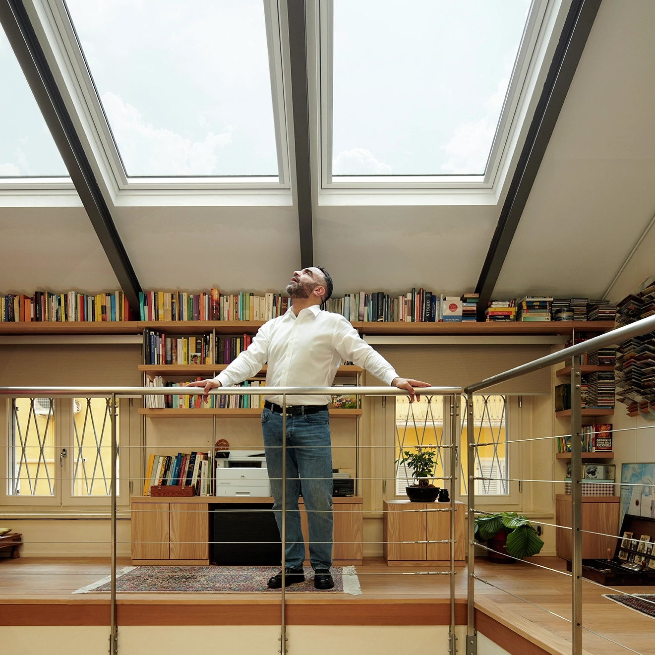 Attic library with VELUX roof windows, bookshelves, and a man standing.