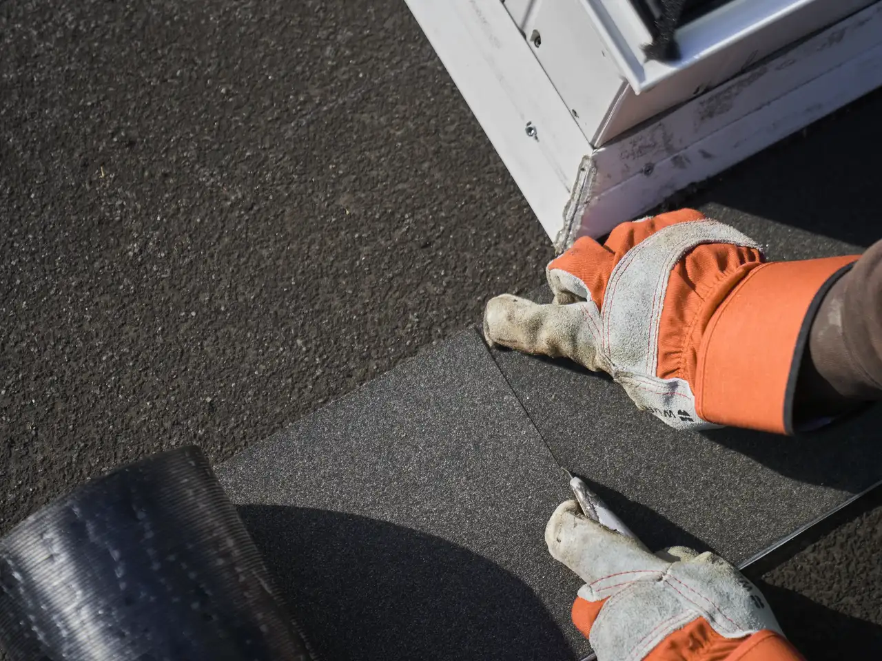 Le mani di un artigiano tagliano il materiale di copertura di una finestra per tetti piani | Rivista VELUX