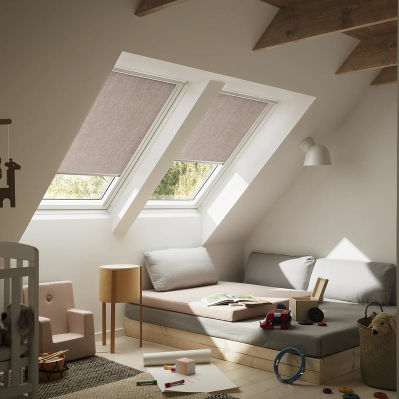 Attic kids room with sloped ceiling and VELUX roof windows, toys and seating area.