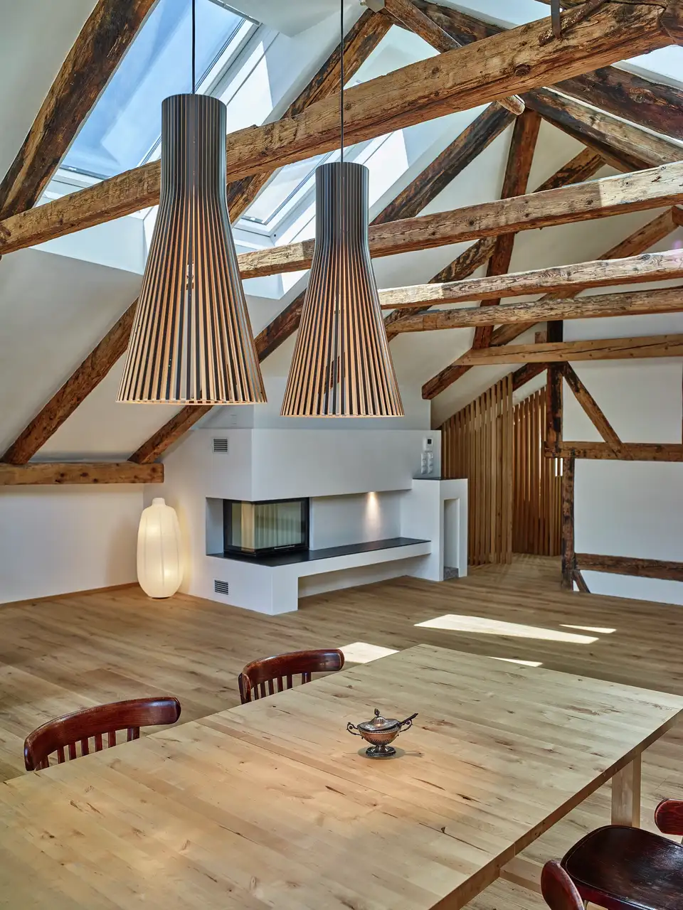 Mansarda in stile rustico con travi in legno a vista, pavimento in legno e finestre per tetti VELUX.