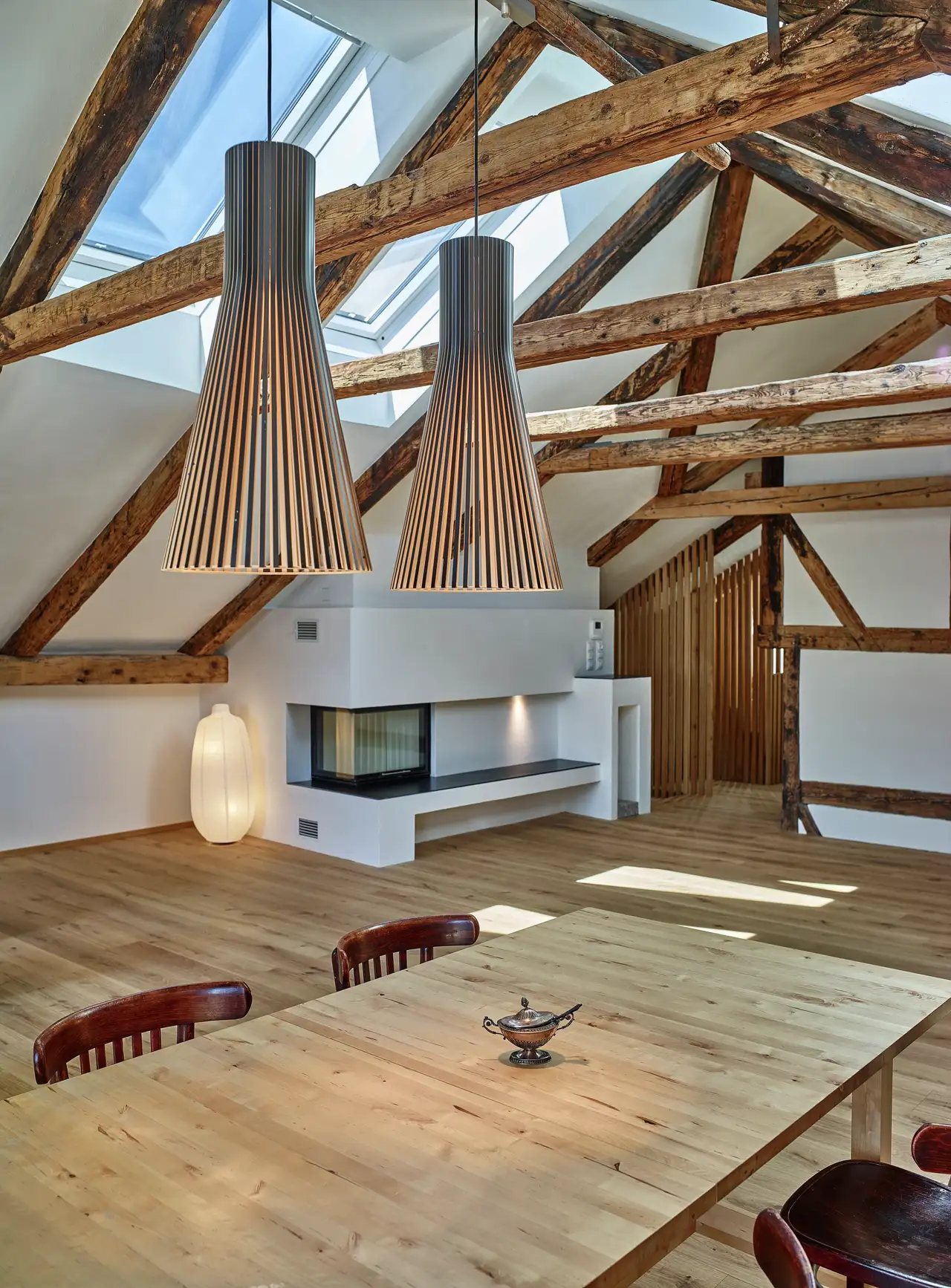combles de style rustique avec poutres apparentes en bois, parquet et fenêtres de toit VELUX