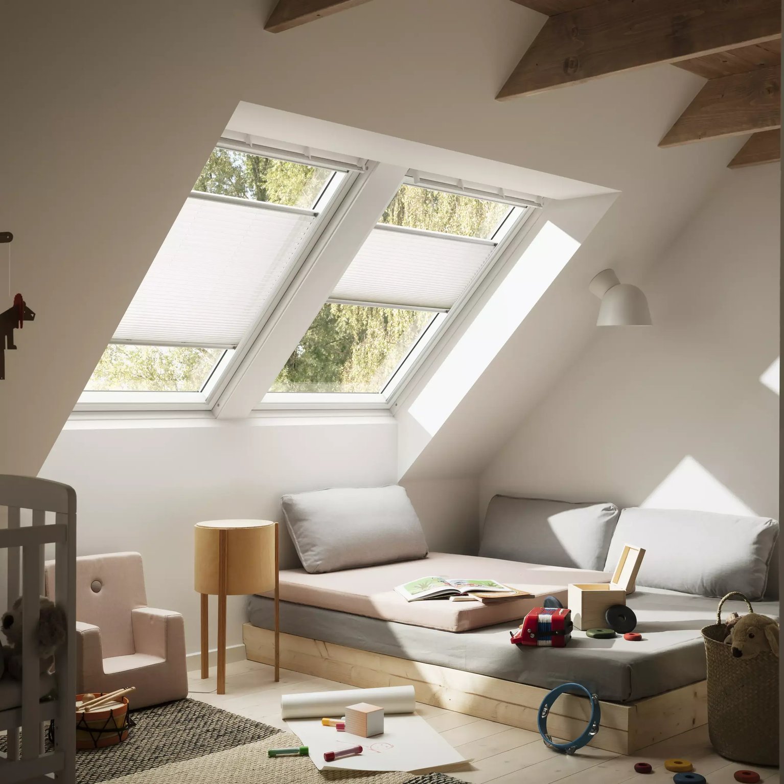 Attic kids room with sloped ceiling, VELUX roof windows, and playful decor.