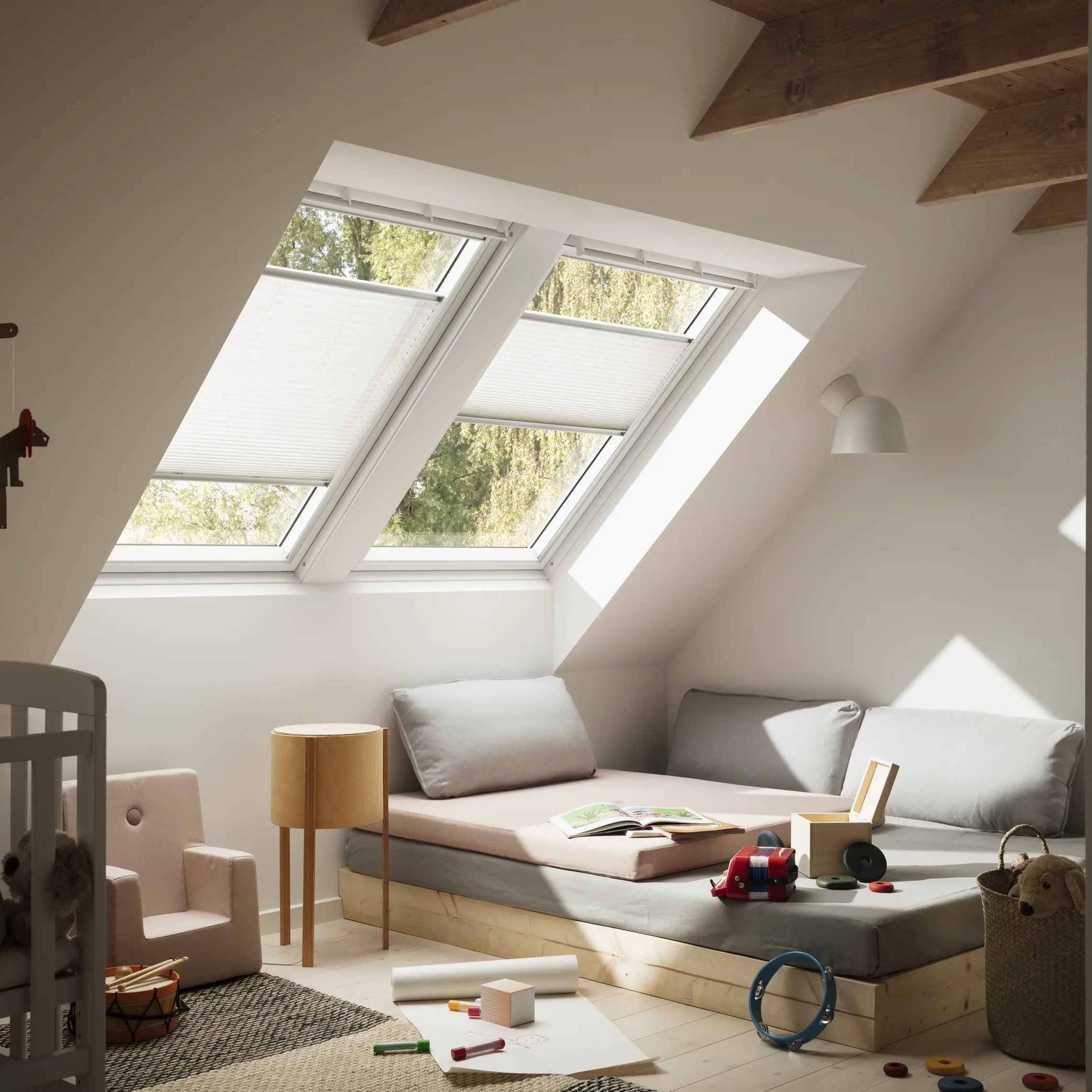 Attic kids room with sloped ceiling, VELUX roof windows, and playful decor.