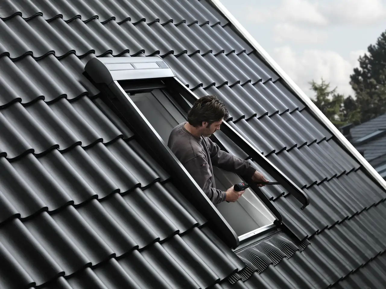 Un installatore procede all’installazione di una tapparella in alluminio su una finestra per tetti.
