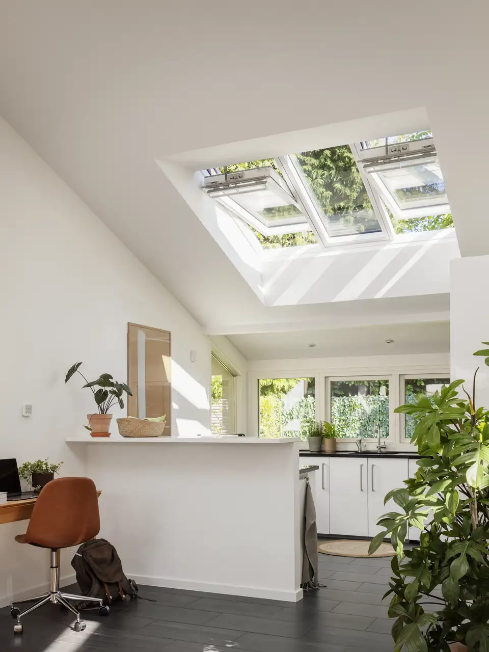 Cucina aperta con soffitti spioventi, finestre per tetti, e un'isola che la separa dalla zona home office.