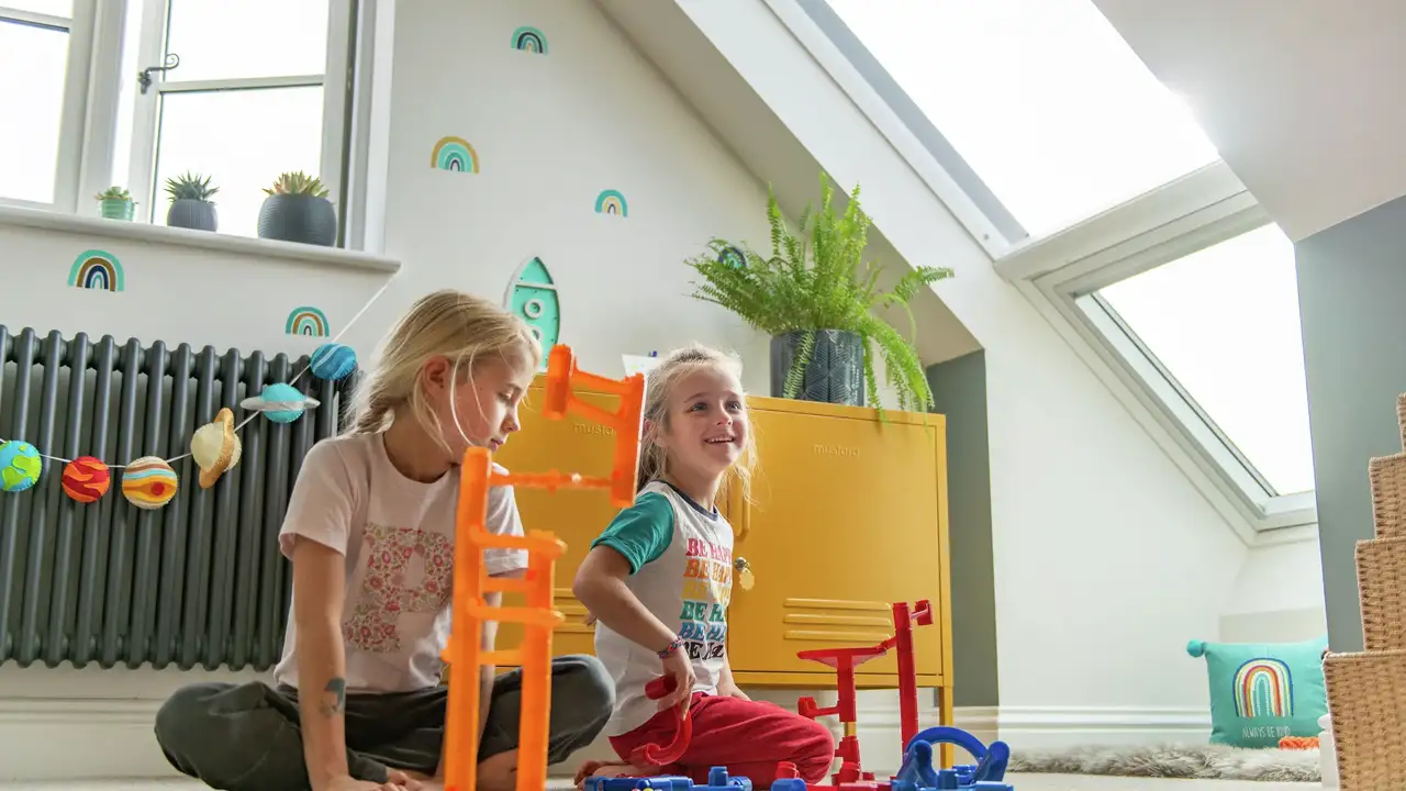 Loft kid’s bedroom with toys, sloped ceiling and large roof window
