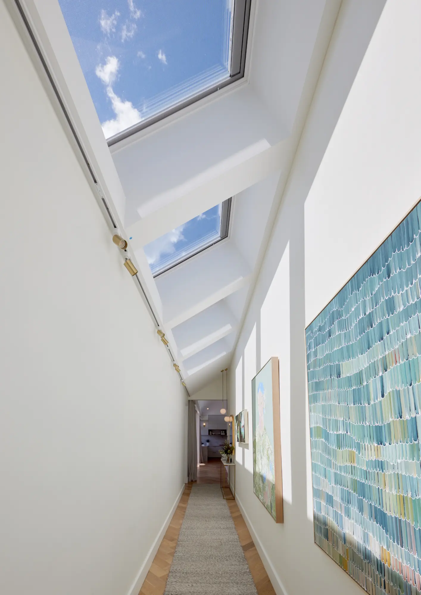 Corridor with sloped ceiling and VELUX roof windows, bright and airy.