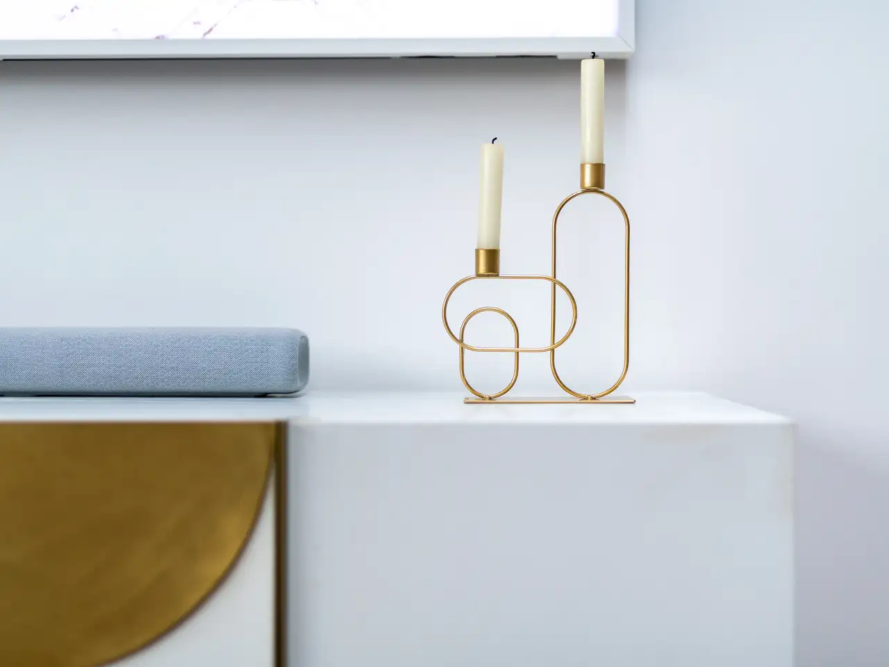 Stilvoller goldener Kerzenständer mit zwei weißen Stabkerzen auf Kommode | VELUX Magazin