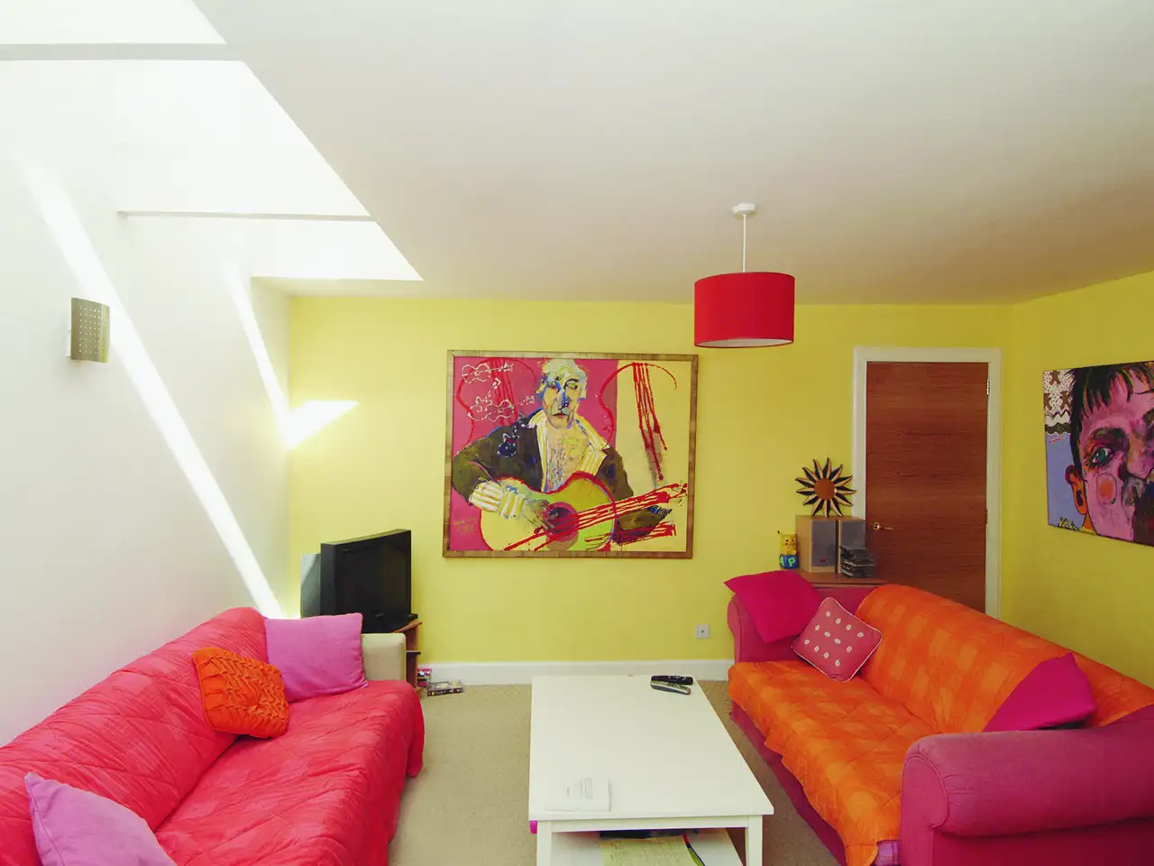 Dopamine Decor Wohnzimmer mit gelben Wänden, pinken Sofas und Skylights | VELUX Magazin