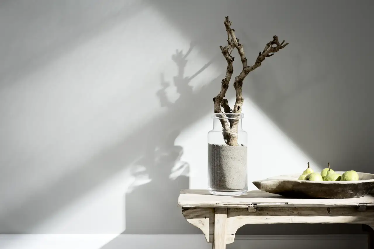 Mit Sand befüllte Vase neben hölzerner Obstschale vor weißer Wand | VELUX Magazin