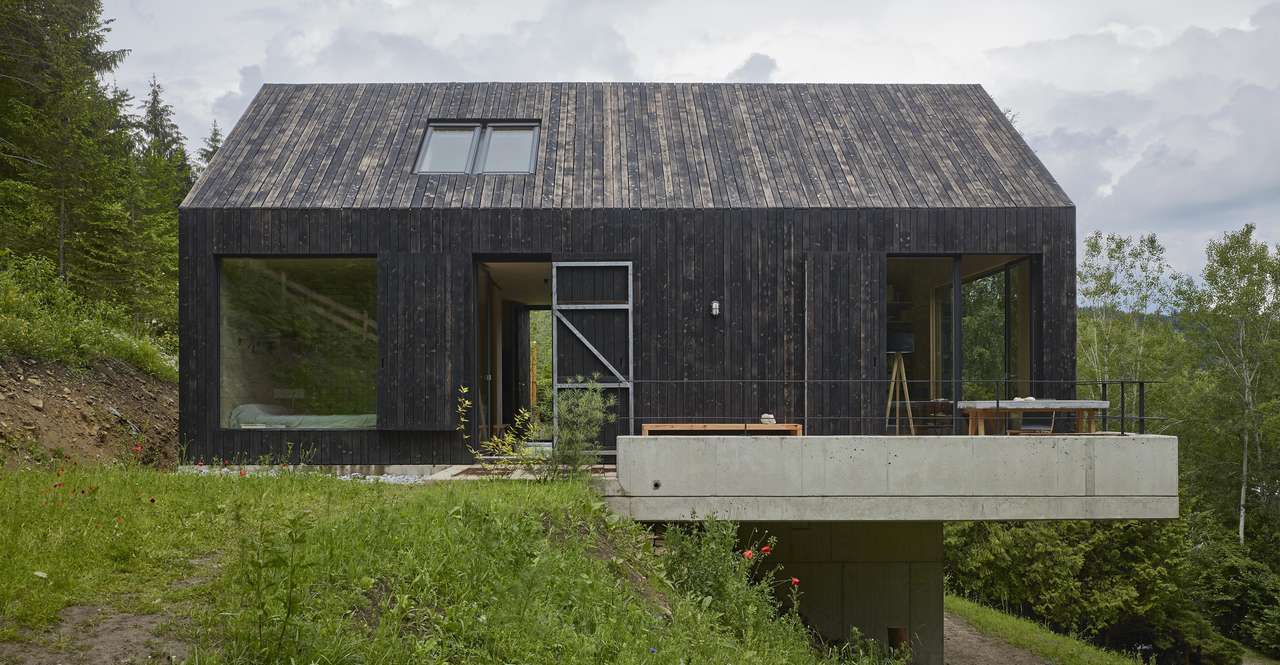 Zeitgenössisches schwarzes Einfamilienhaus mit VELUX Dachflächenfenster im Wald.