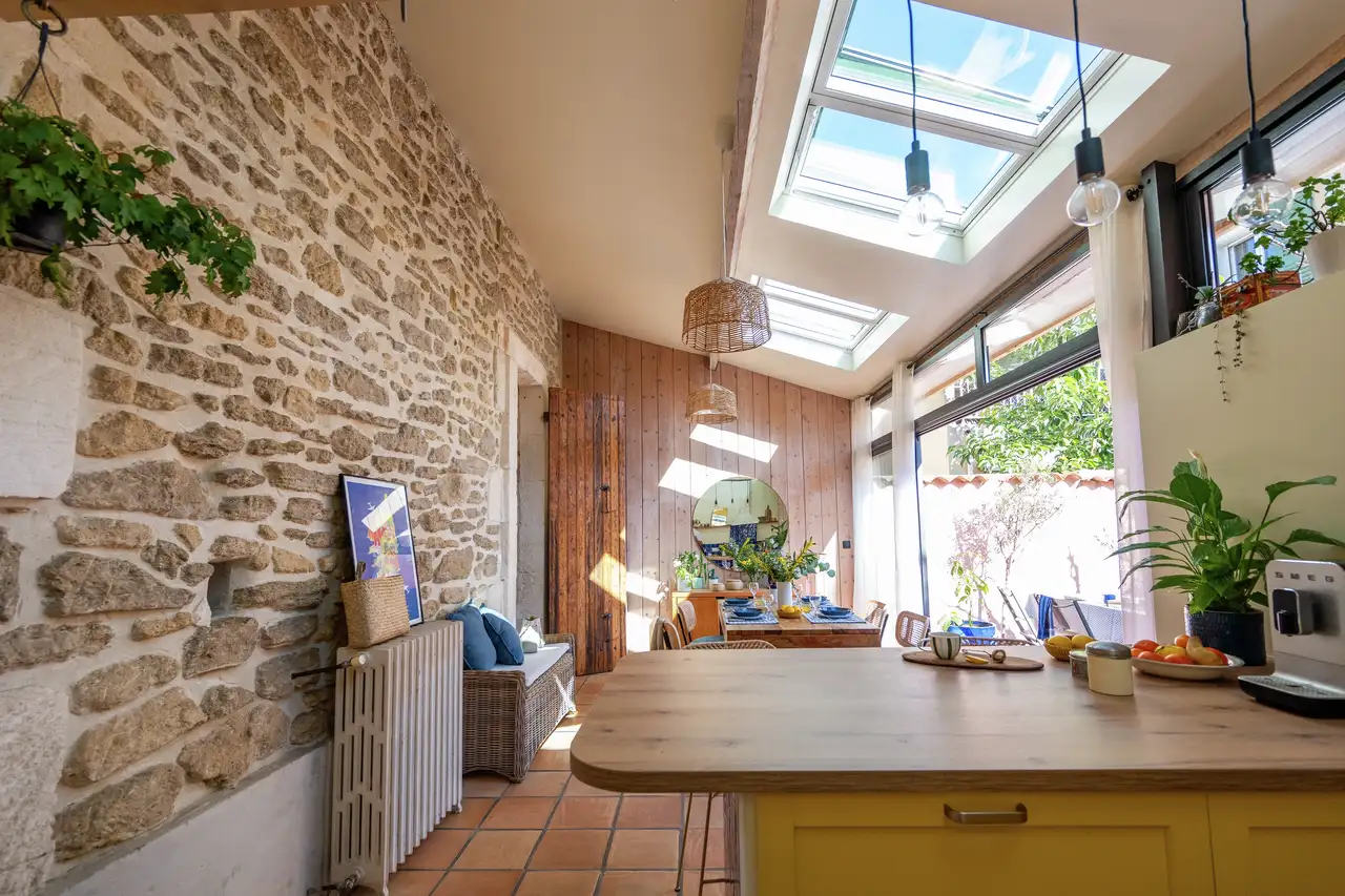 Cucina in stile rustico con parete in pietra a vista, pavimento in cotto e finestre per tetti che illuminano lo spazio