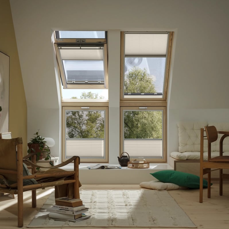 Attic room with sloped ceiling, VELUX roof windows, and cozy furnishings.