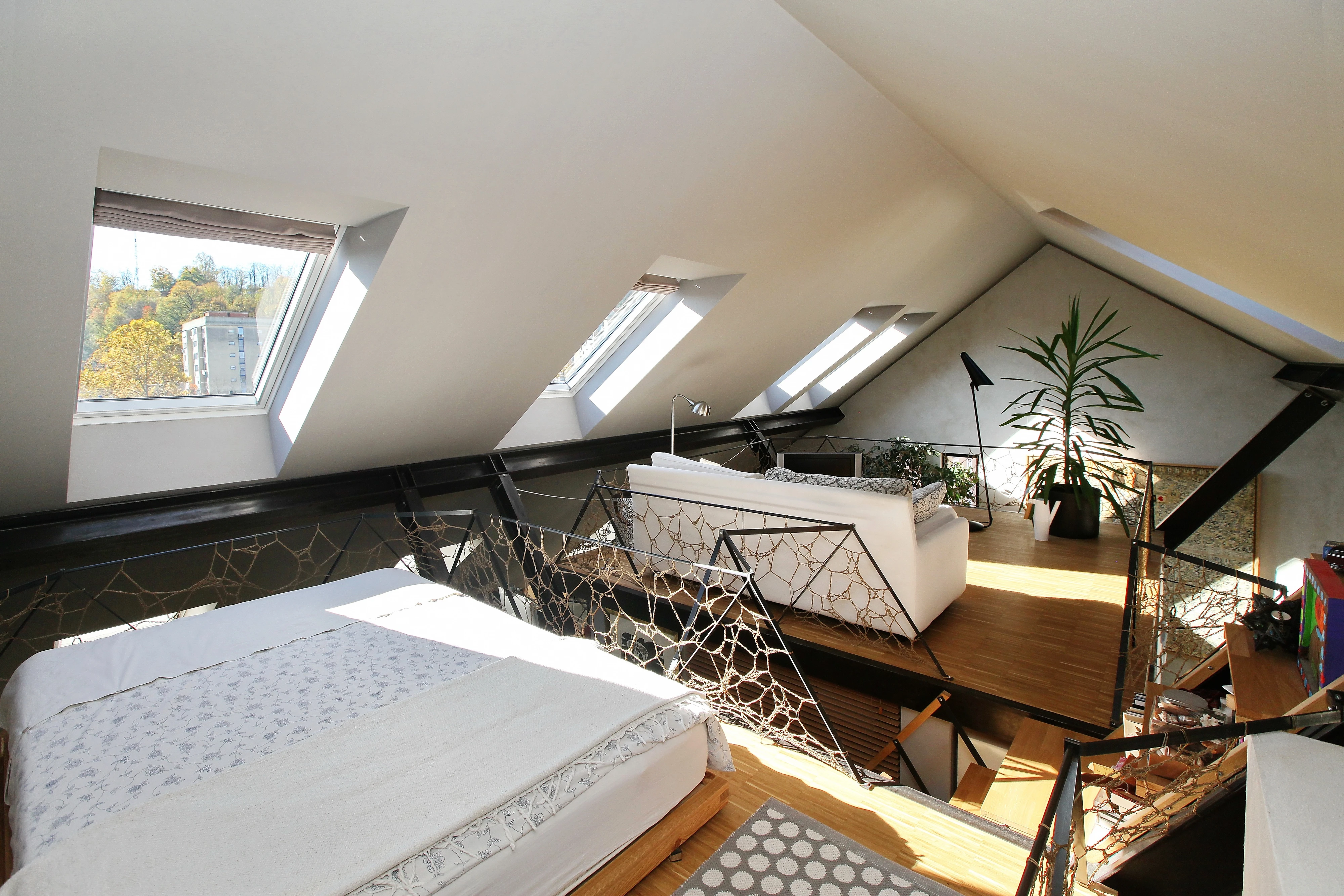 Attic living space with sloped ceiling and VELUX roof windows, modern furnishings.