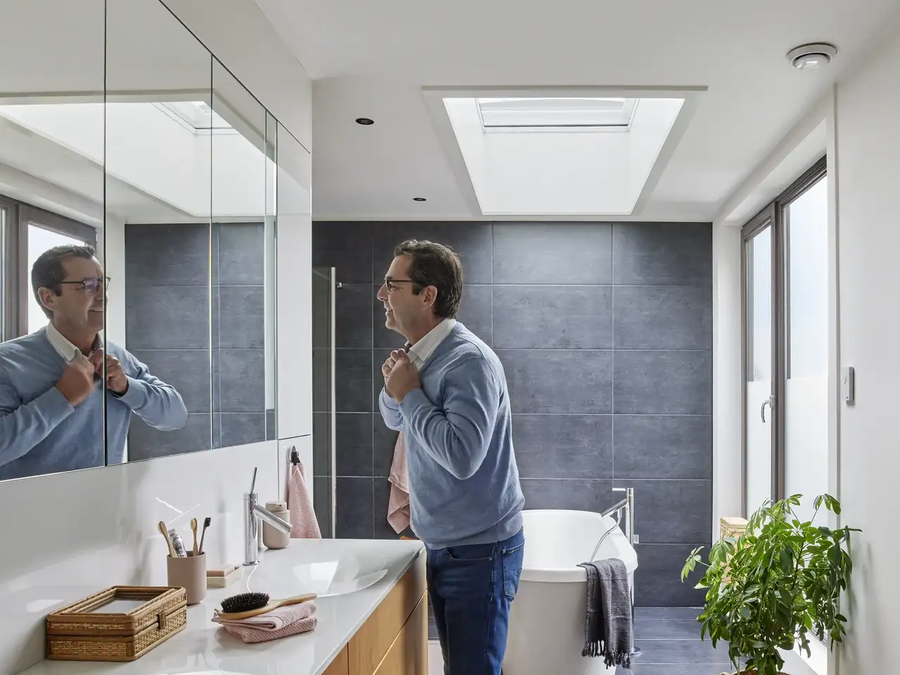 Uomo davanti allo specchio del bagno in un moderno bagno con lucernario | Rivista VELUX