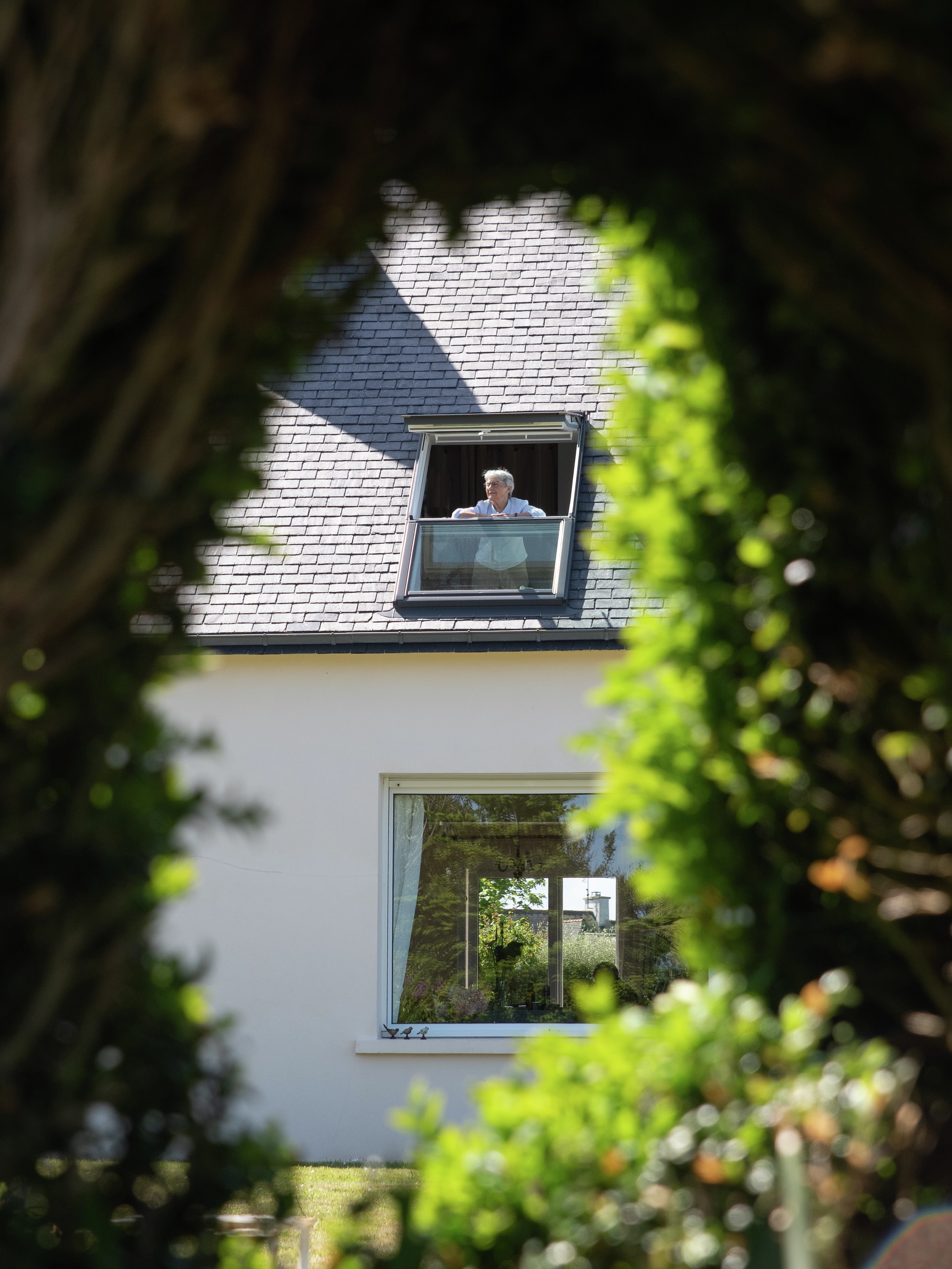 femme regardant par la verrière plane VELUX de sa maison de campagne