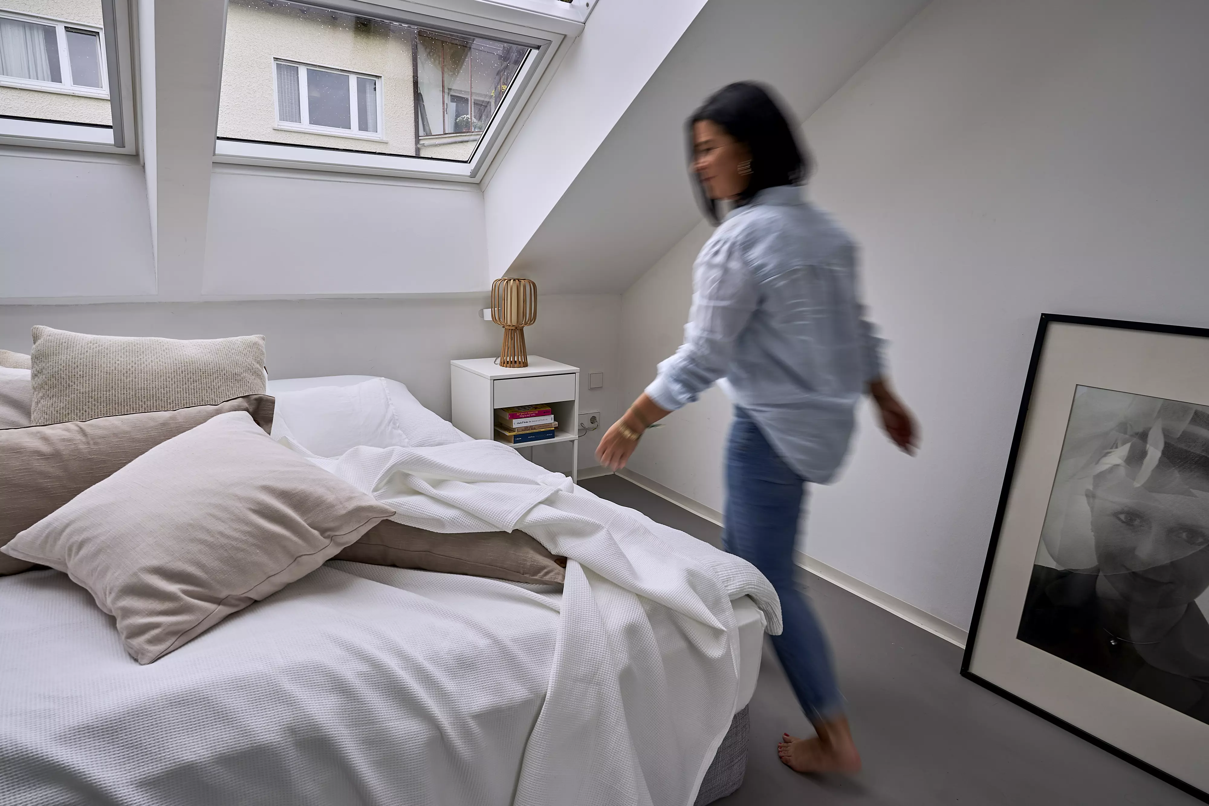 Gemütliches Dachboden-Schlafzimmer mit natürlichem Licht von einem VELUX Dachflächenfenster, kuscheliger Bettwäsche und moderner Einrichtung.