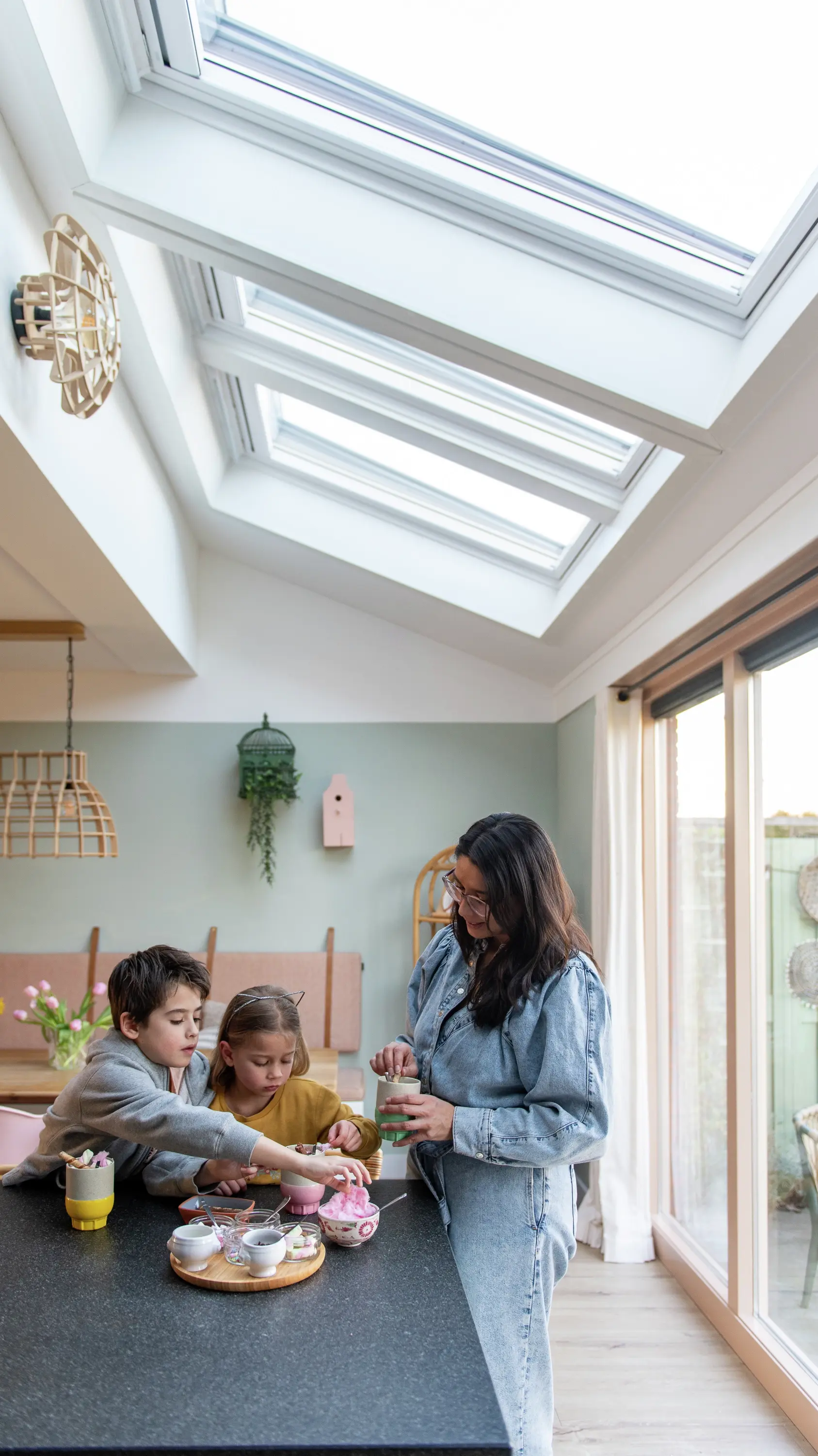 Famille profitant d'une fête du thé dans une cuisine avec des fenêtres de toit VELUX offrant de la lumière naturelle.