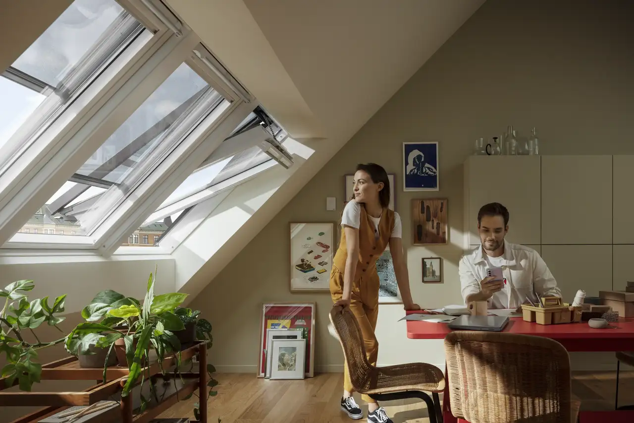 Séjour lumineux équipé de trois fenêtres de toit VELUX avec stores pare-soleil extérieurs.