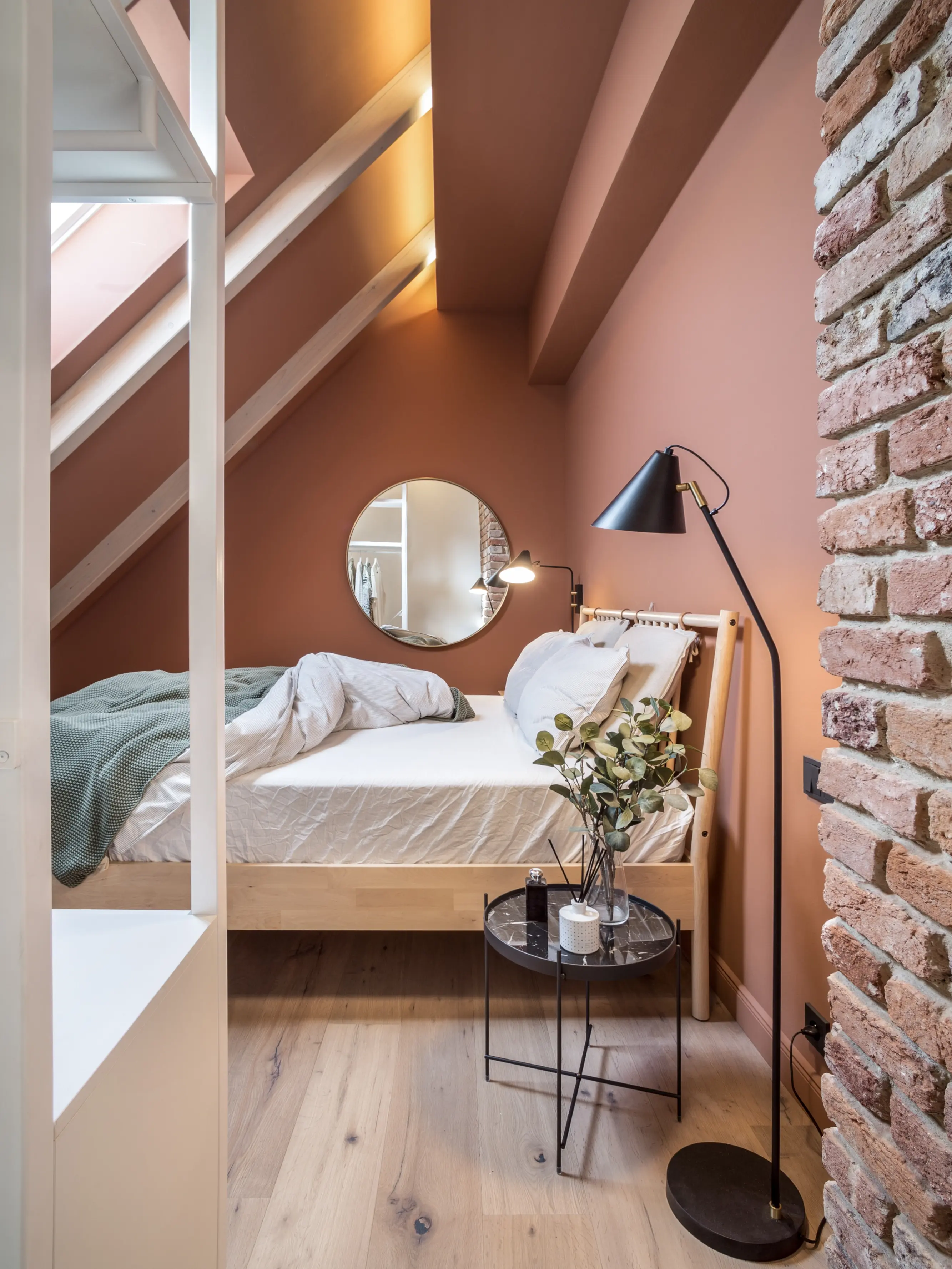 Une chambre douillette et bien éclairée avec un lit confortable, des murs en briques apparentes et une fenêtre Velux qui laisse entrer une lumière naturelle abondante.