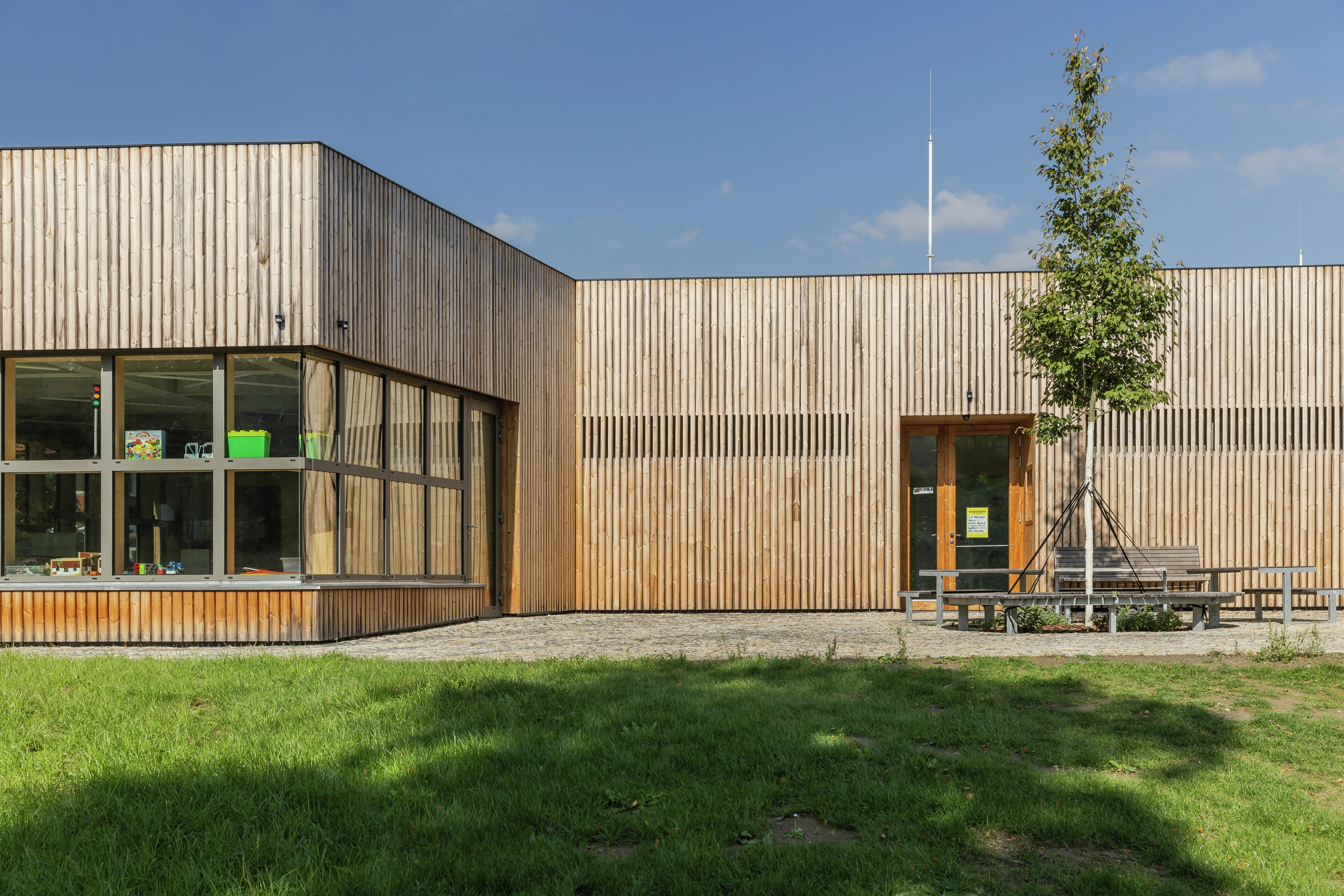 Modern building with wooden facade and large windows.