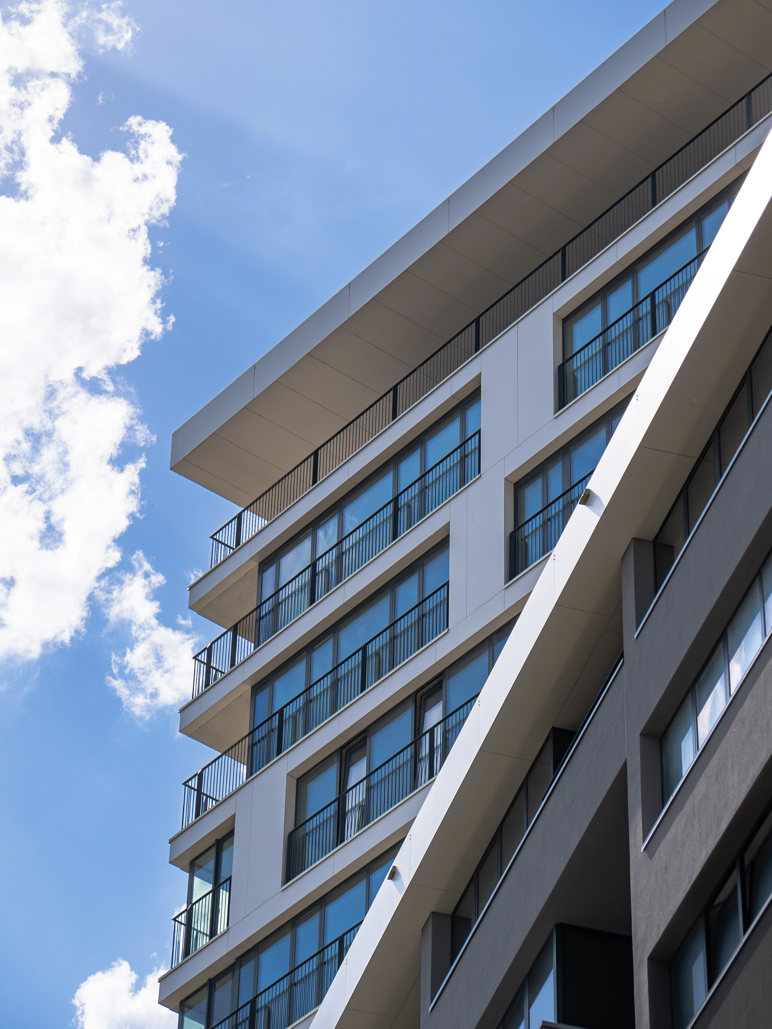 Contemporary apartment building with glass balconies under a clear blue sky.