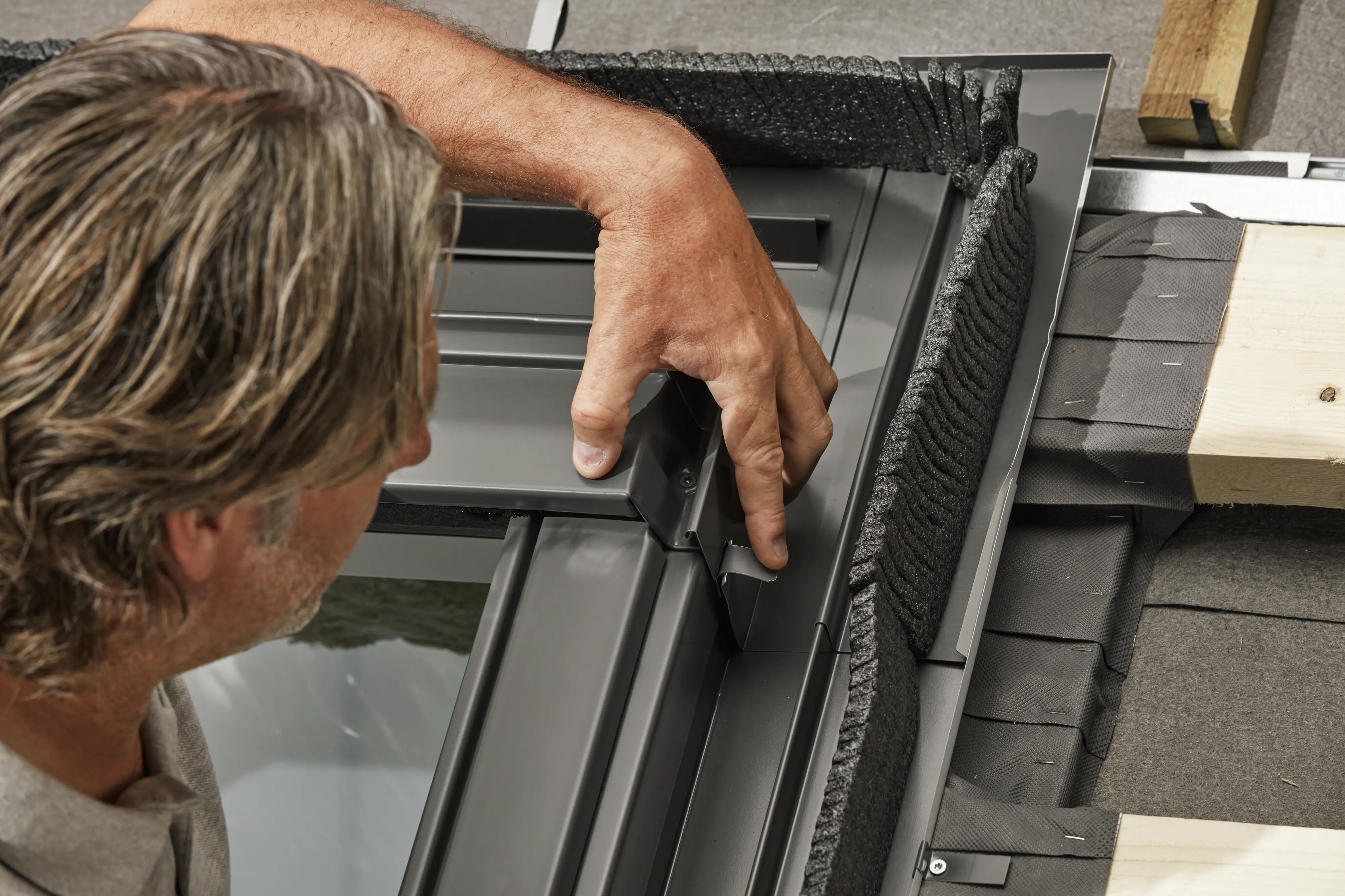 Detailný záber na montáž strešného okna VELUX s izoláciou a drevenými trámami.