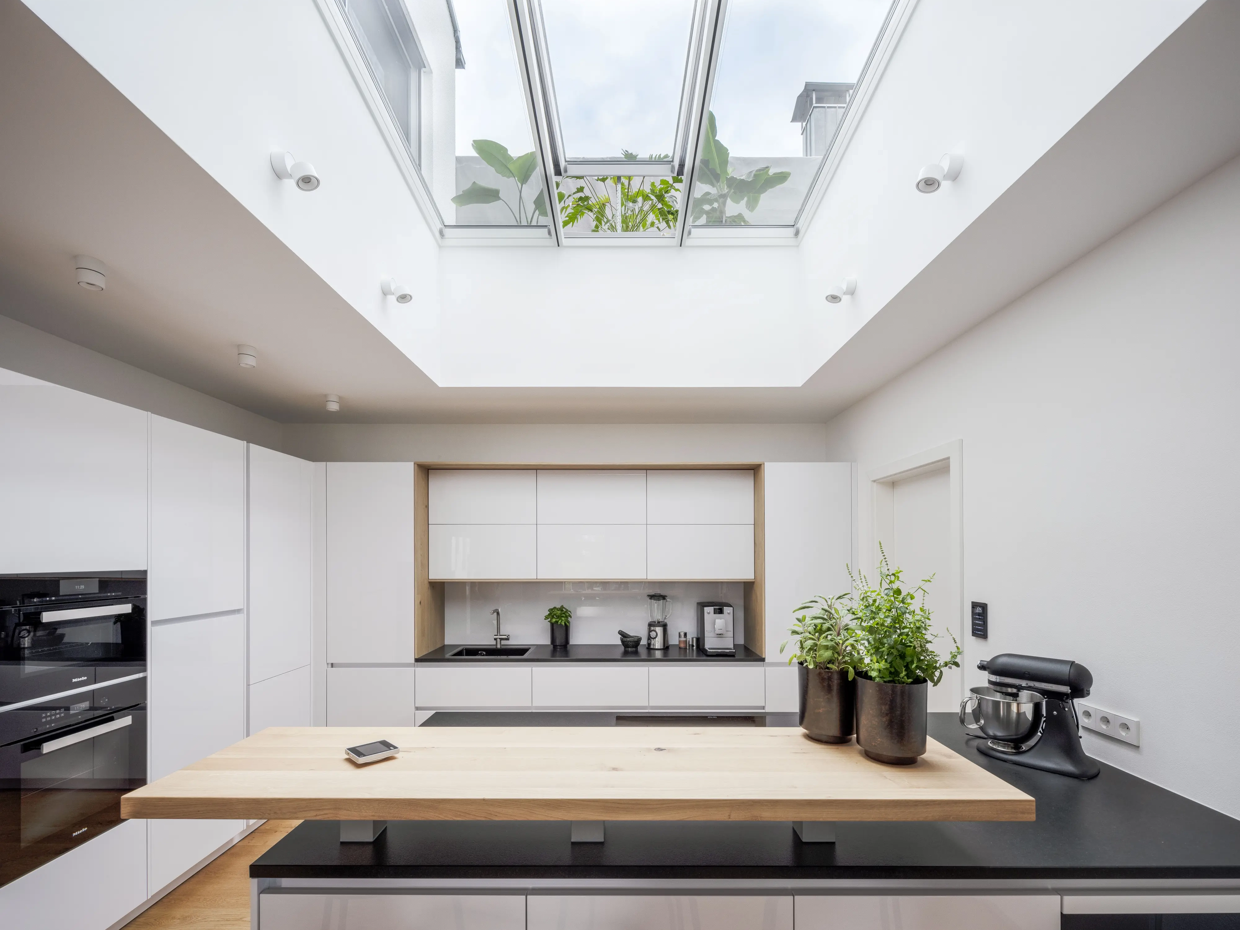 Modern kitchen with white cabinets and VELUX roof window, bright and airy.