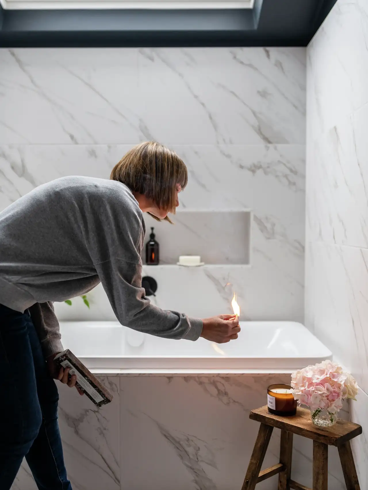 Frau entzündet Duftkerze im modernen Badezimmer unterm Dach | VELUX Magazin