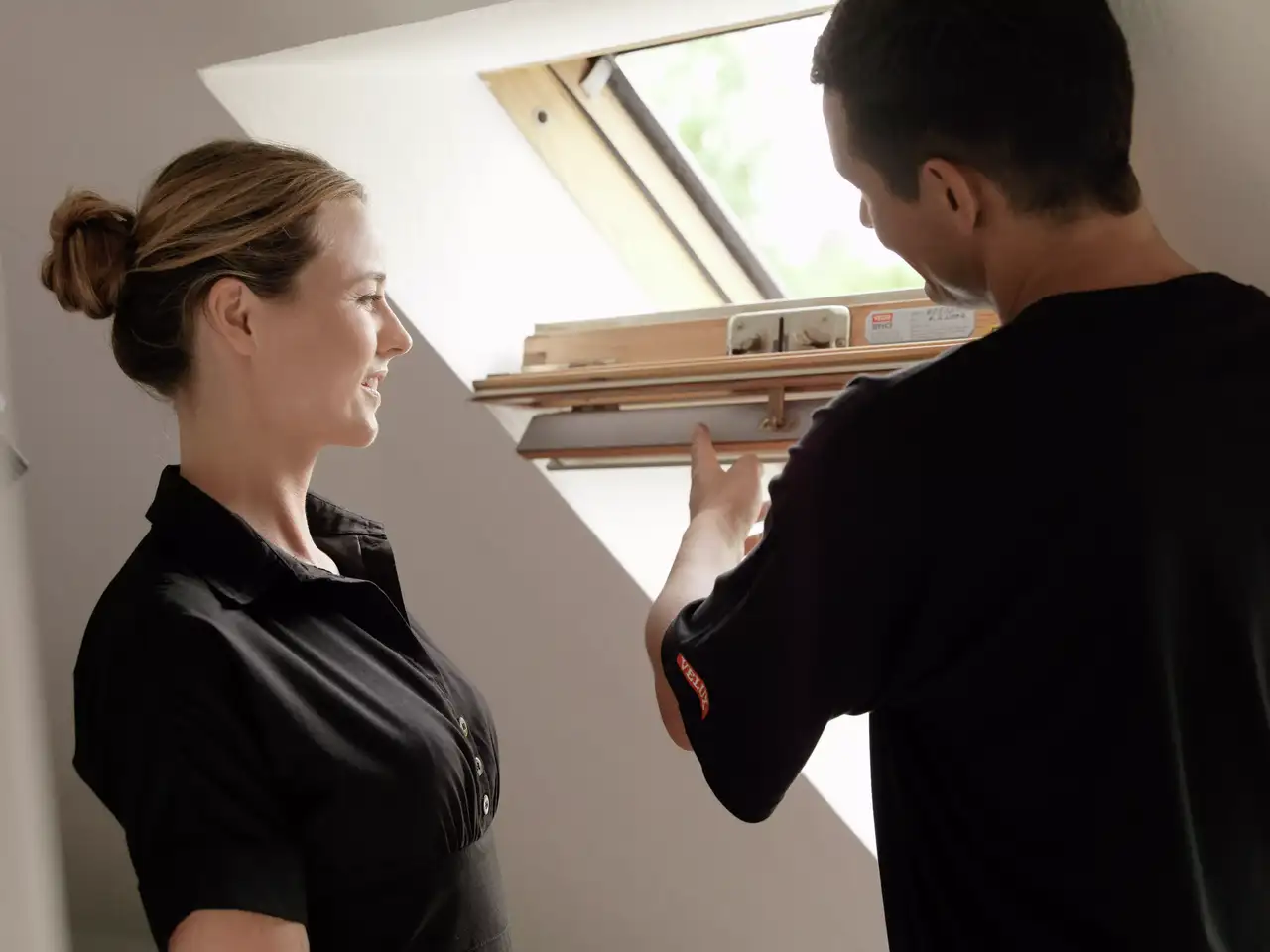 Einbauer erklärt dem Hausbesitzer im Dachgeschoss die Eigenschaften des VELUX Dachflächenfensters.