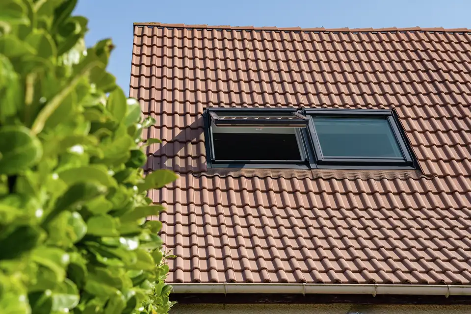Dakramen naast elkaar geplaatst op een pannendak, gedeeltelijk geopend voor een goede ventilatie