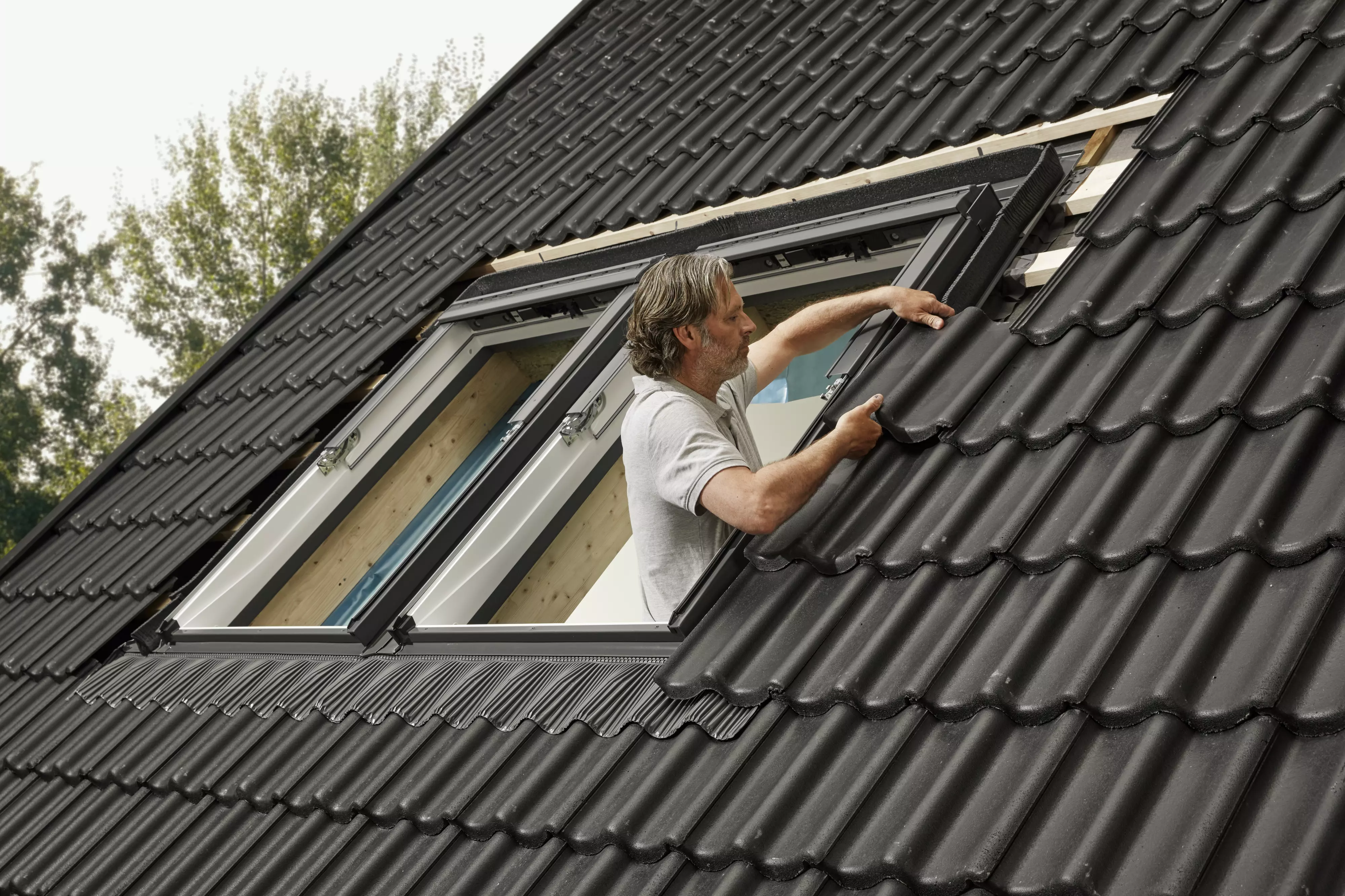 Installation professionnelle d'une fenêtre de toit VELUX sur un toit en tuiles.