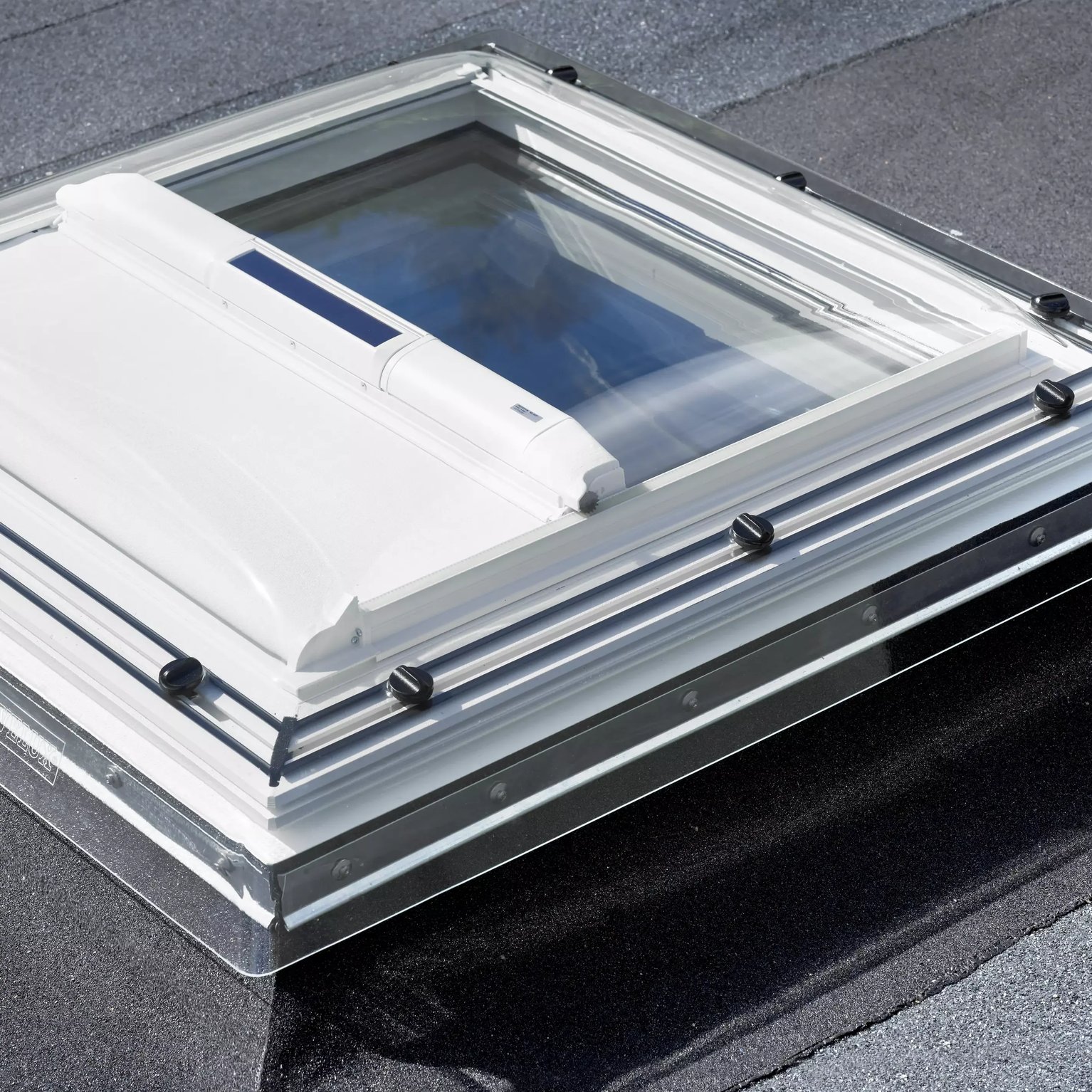 VELUX roof window on flat roof with roofing felt material.