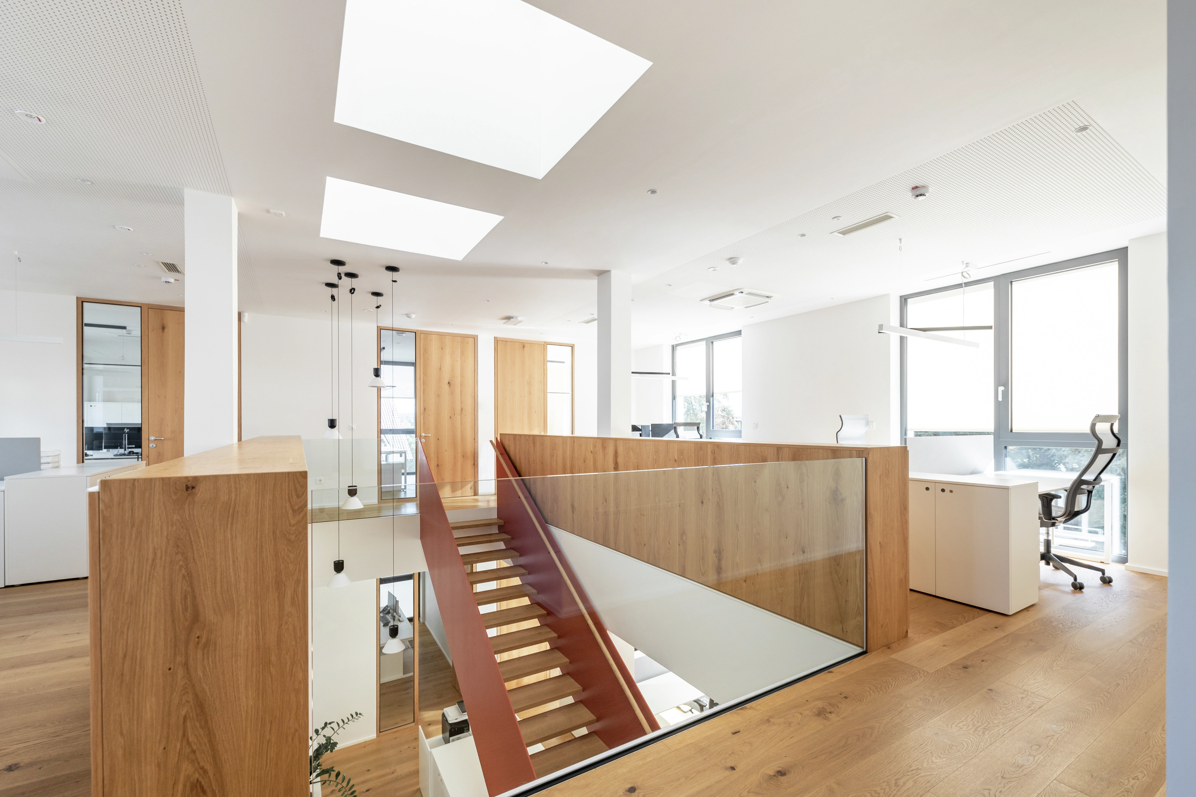 Moderní kancelářský prostor se střešními okny VELUX, dřevěnou podlahou a elegantním schodištěm