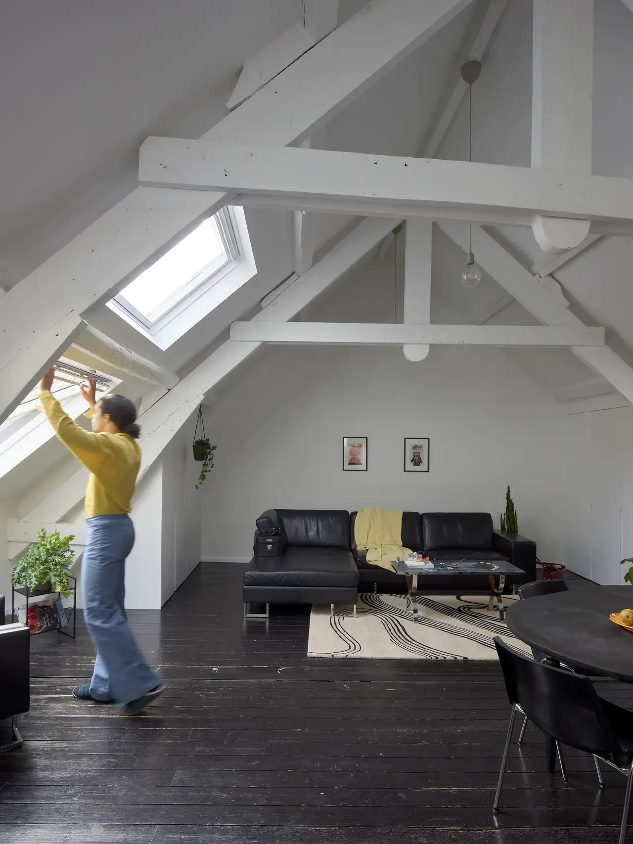 Salón con tejado inclinado, vigas y ventanas de tejado.