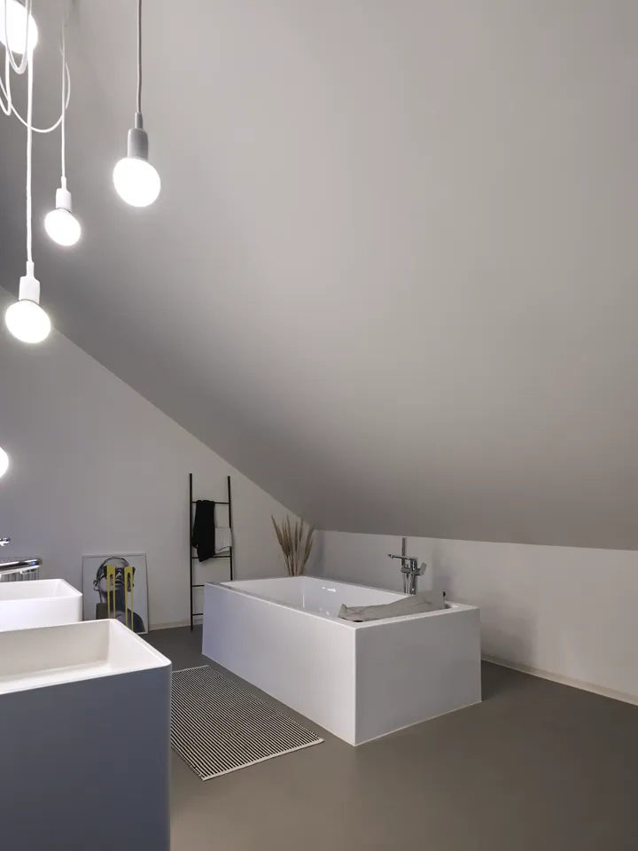 Vorher – dunkles Badezimmer unter Dachschräge mit freistehender Badewanne, Badematte und zwei Waschbecken | VELUX Magazin