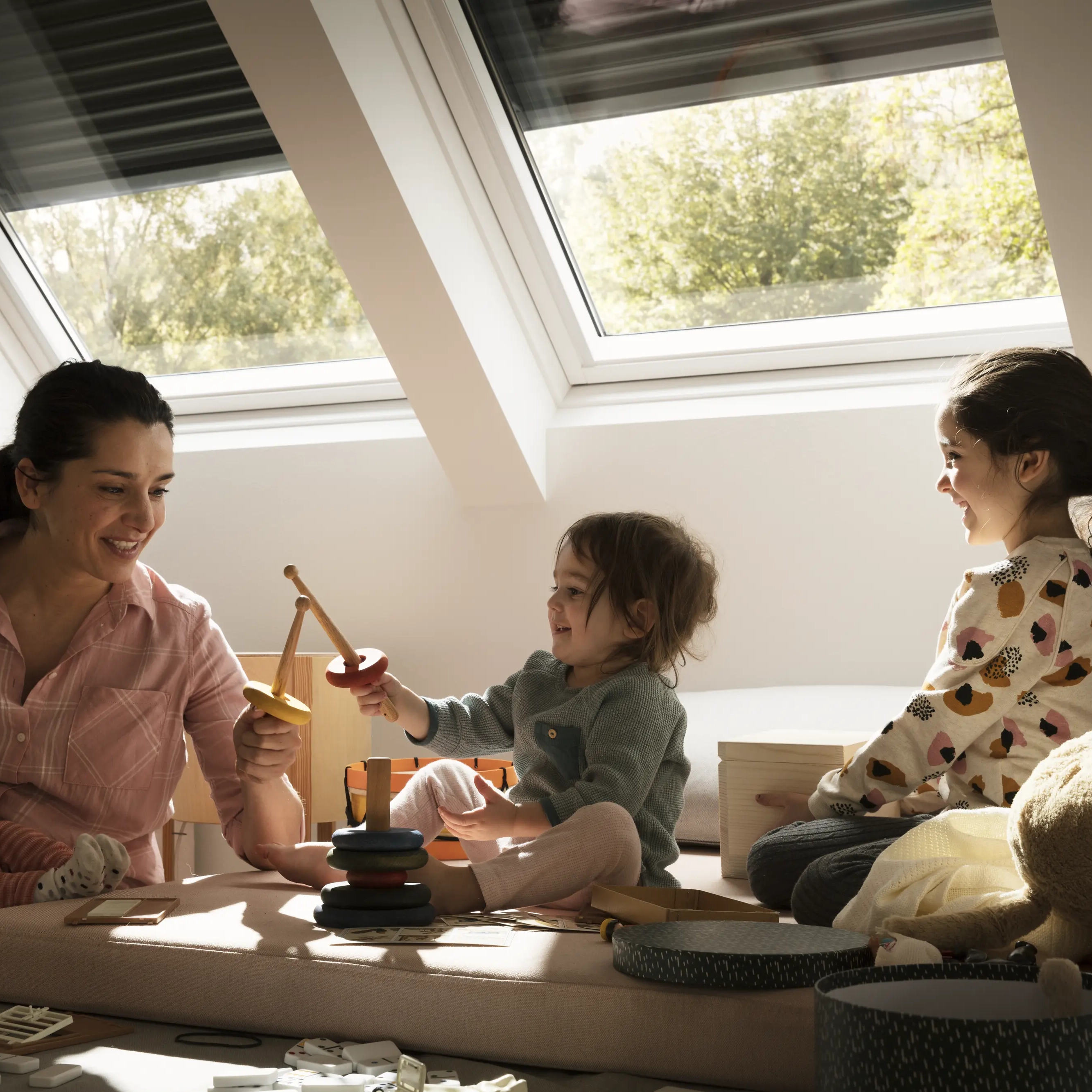 Attic playroom with sloped ceiling and VELUX roof windows, family playing.