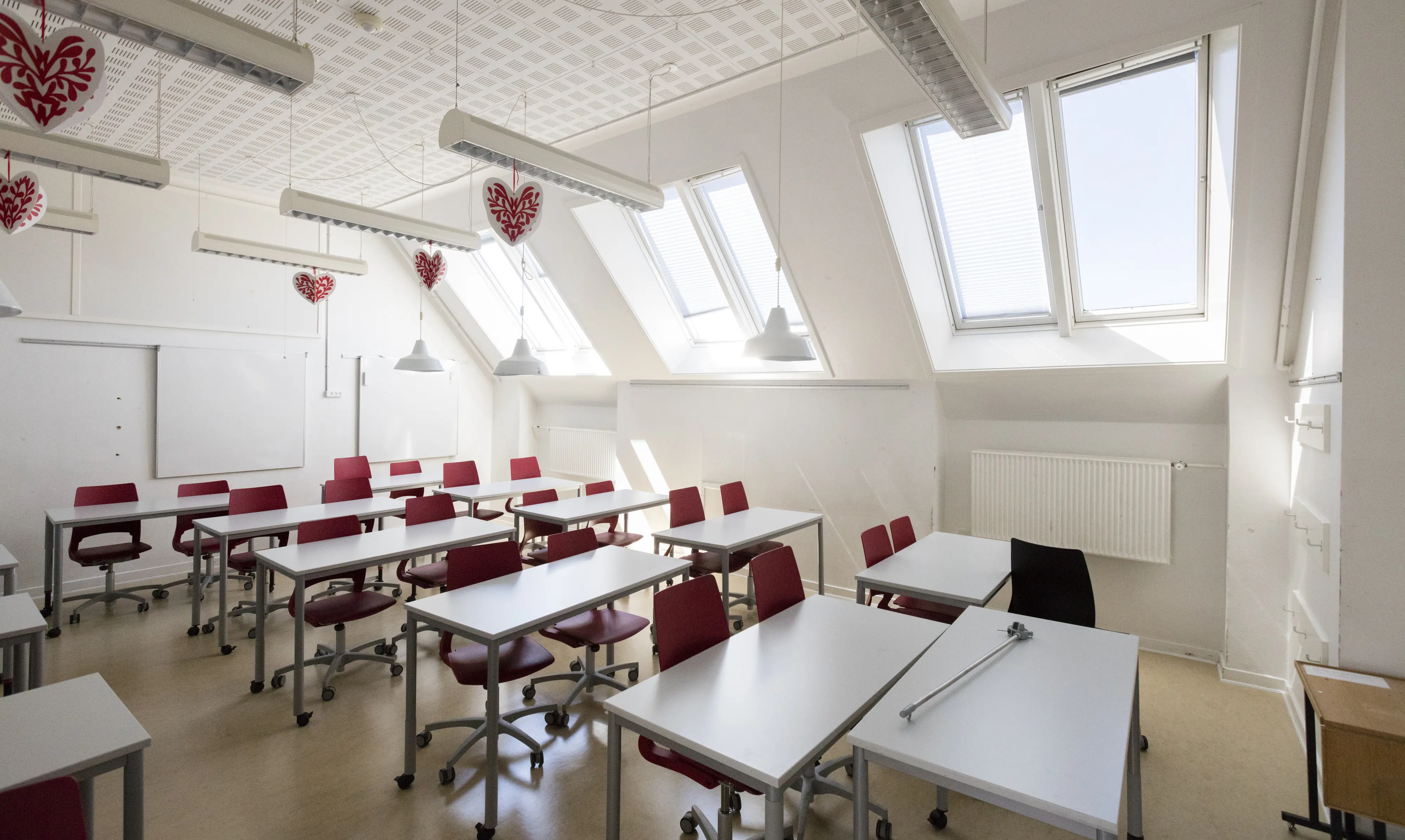 Učionica s kosim stropom i VELUX tavanskim prozorima, modernim i svijetlim namještajem.