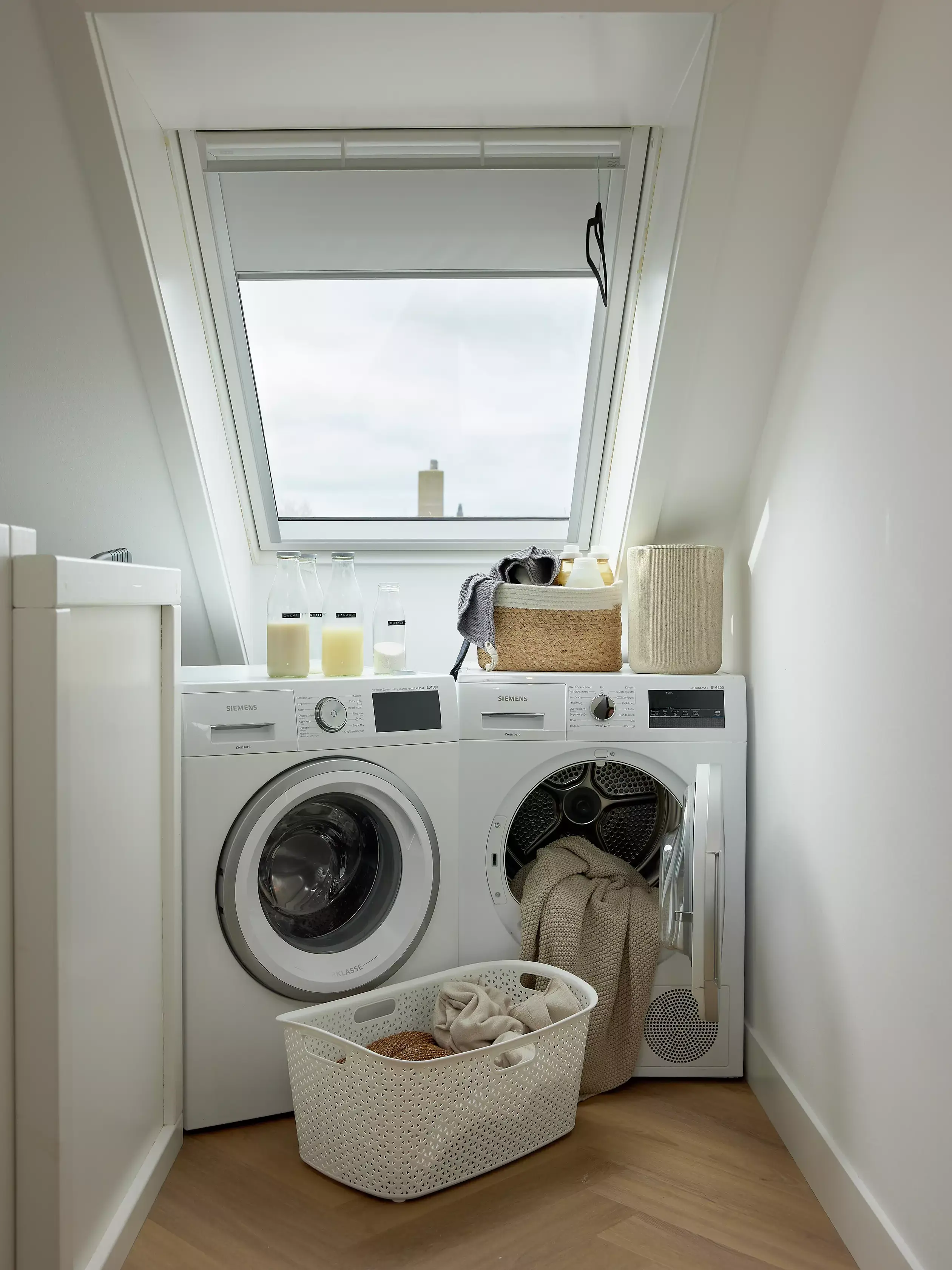 Persona in una stanza di servizio seminterrata con elettrodomestici per la lavanderia e luce naturale proveniente da una finestra.
