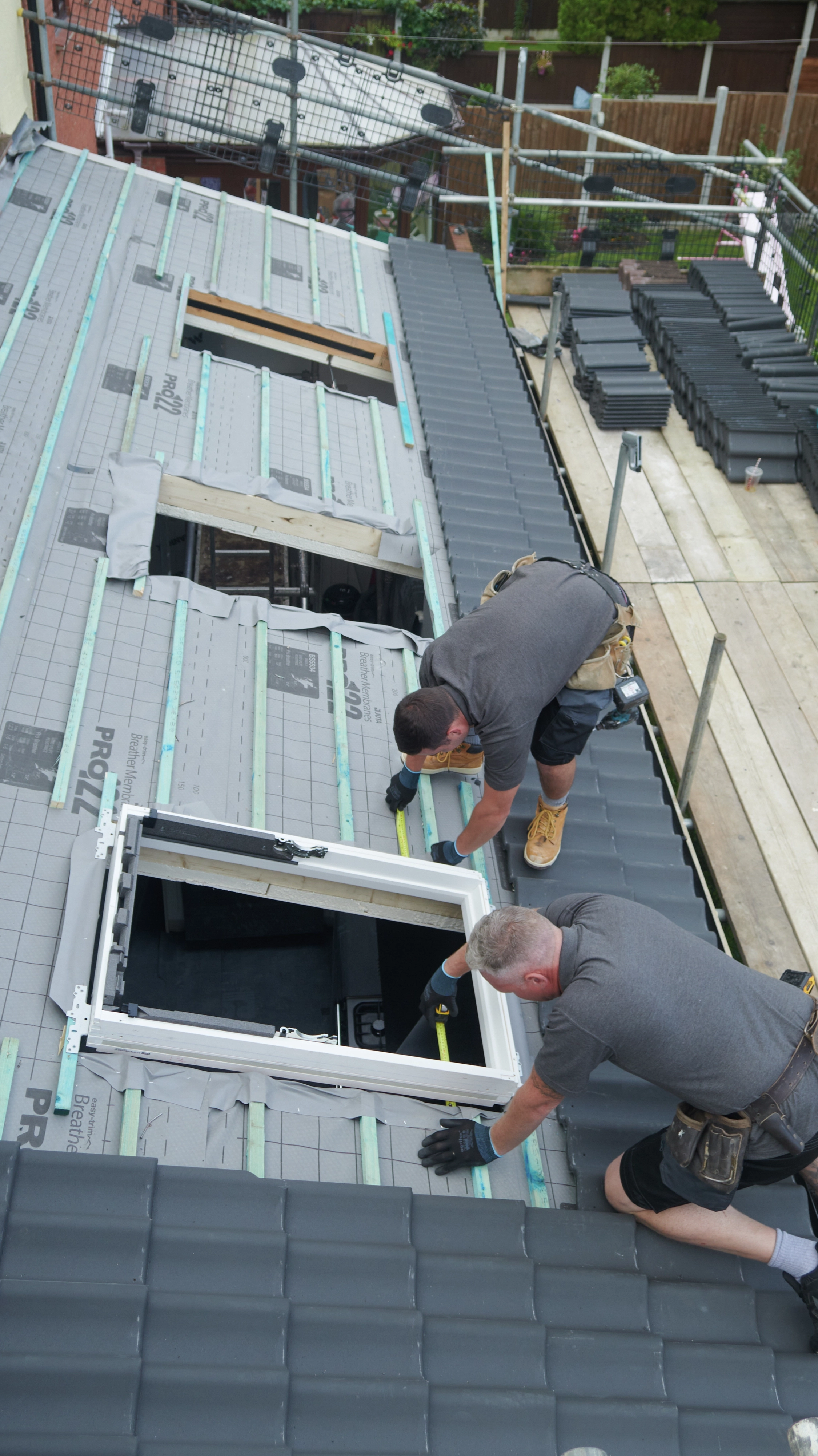 Workers installing a VELUX roof window on a tiled roof.