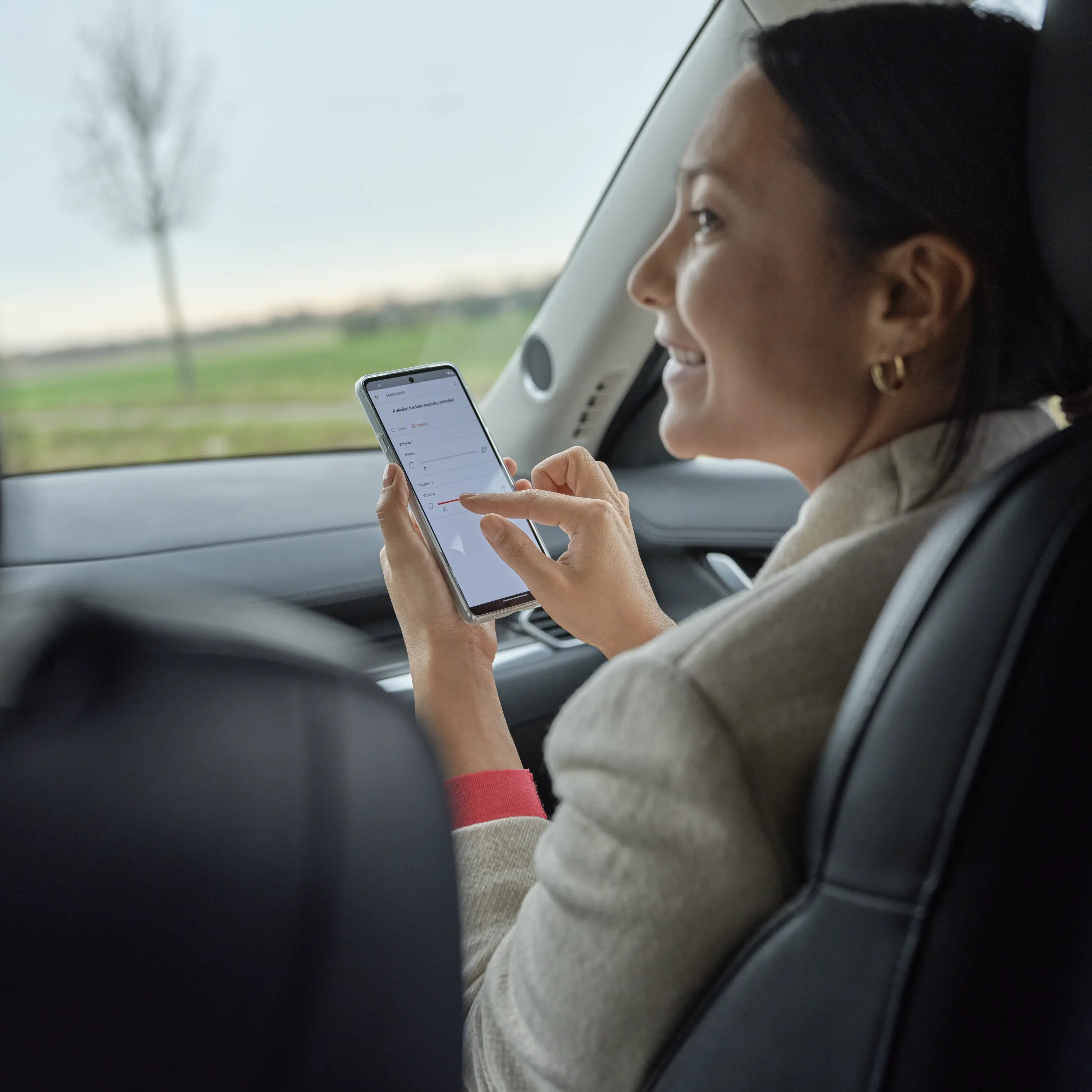 Person in car backseat using smartphone, leather seats visible.
