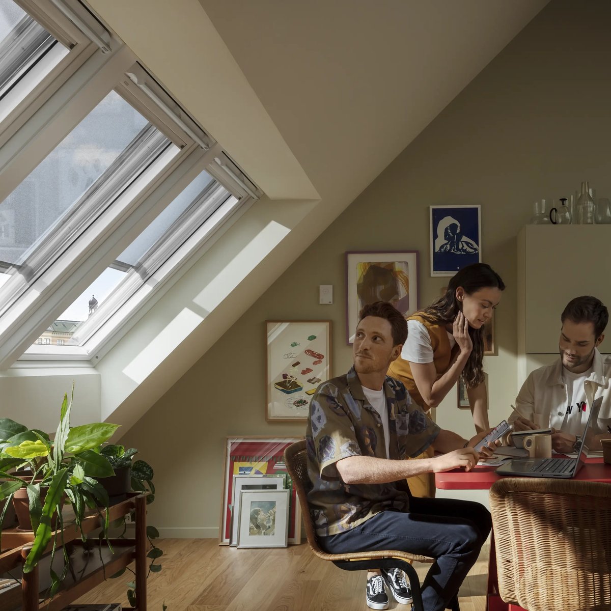 Attic office with VELUX roof windows, red table, and artwork.