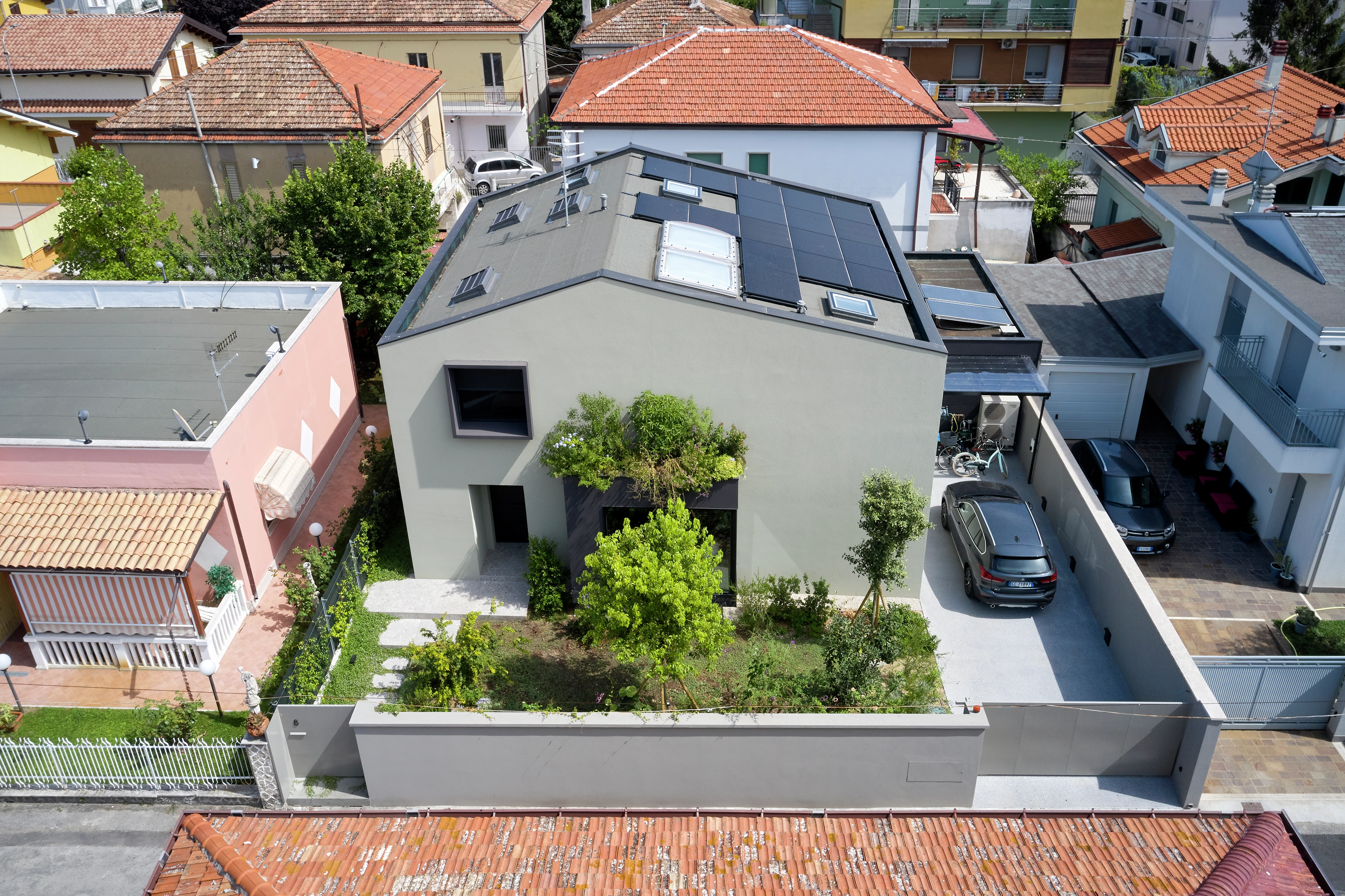 Casa unifamiliare moderna con finestra VELUX e pannelli solari, circondata dal verde.